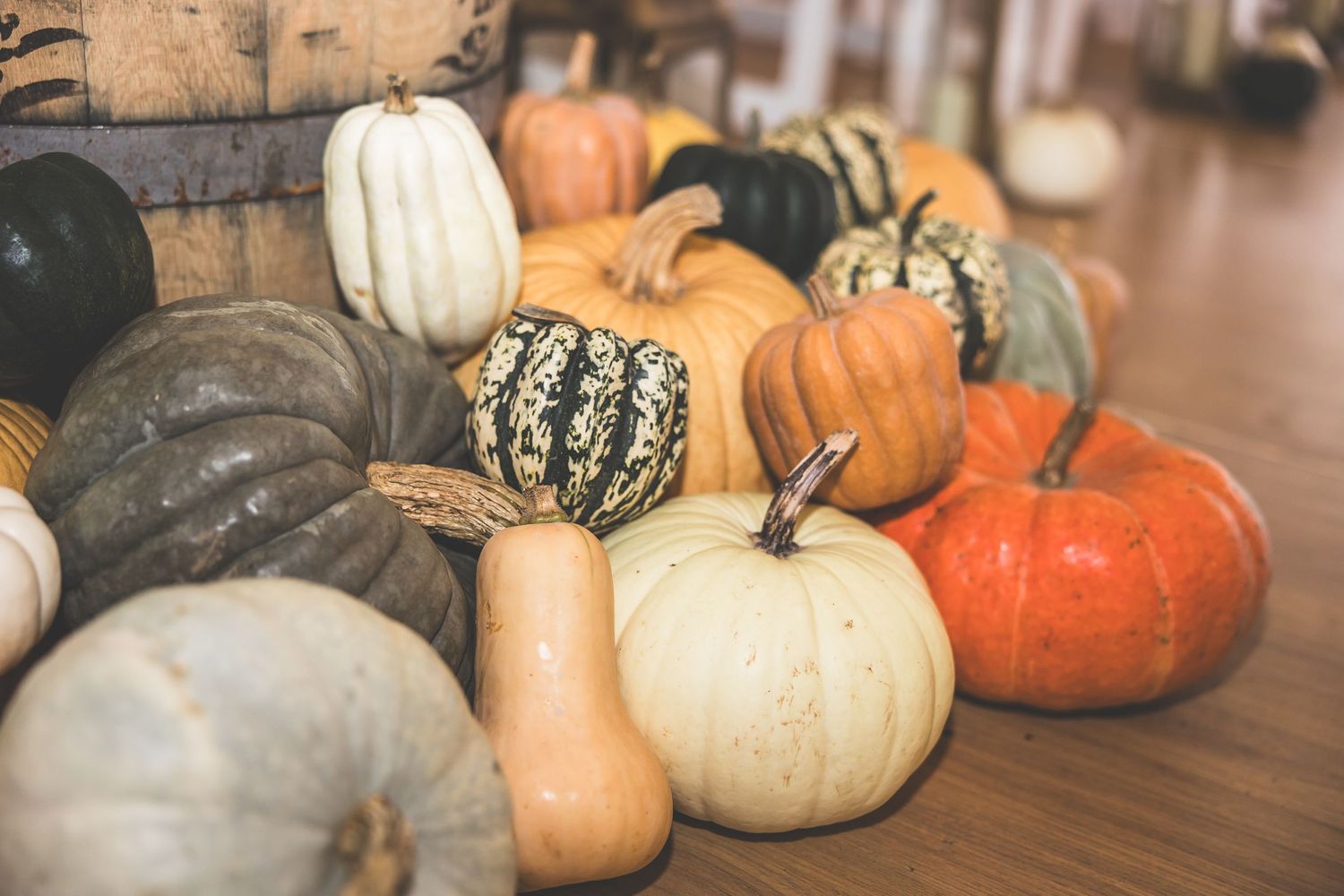 Collection of decorative heirloom pumpkins in various colors and patterns displayed on wooden surface.
