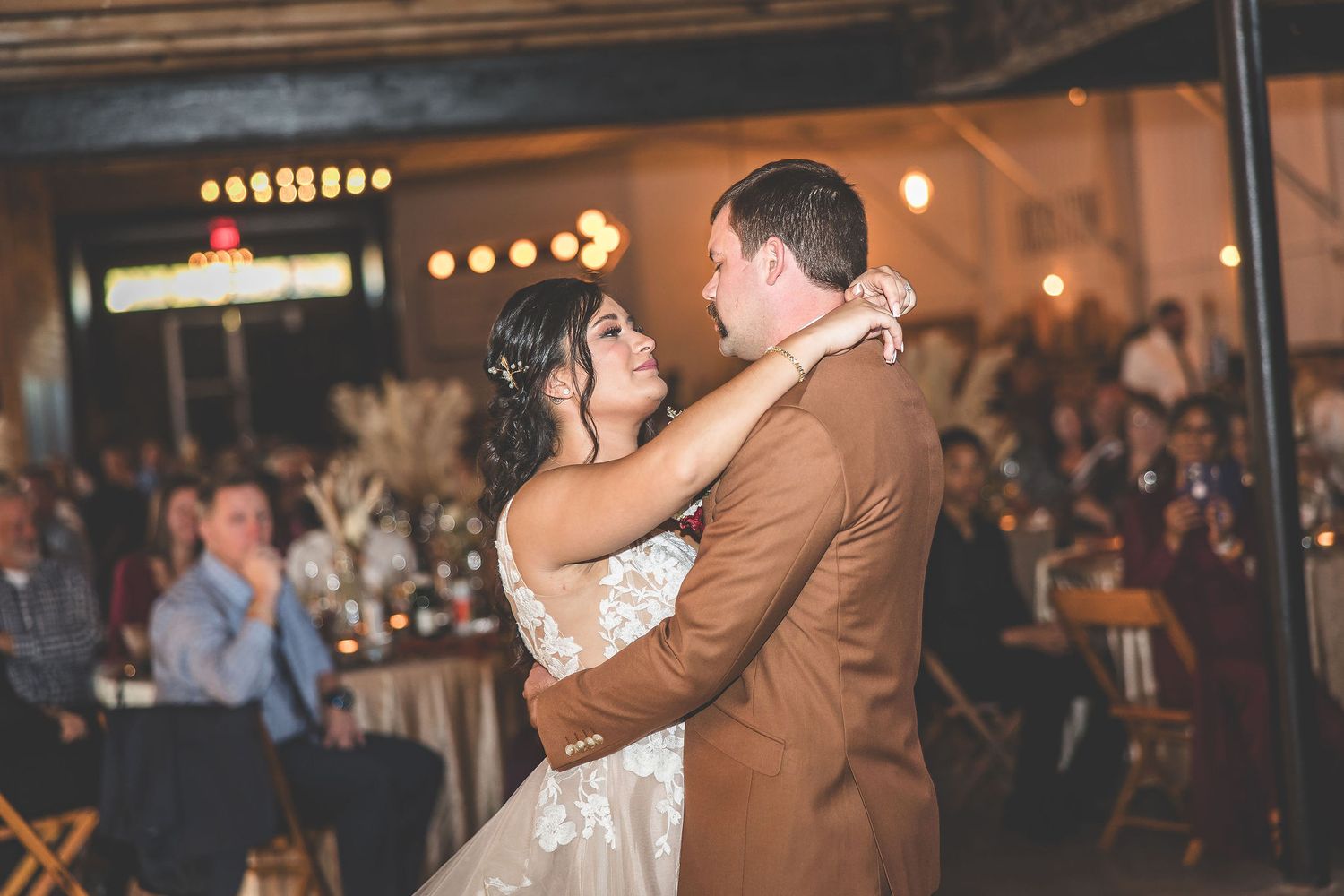 Couples dance together during a romantic moment at rustic barn wedding reception.