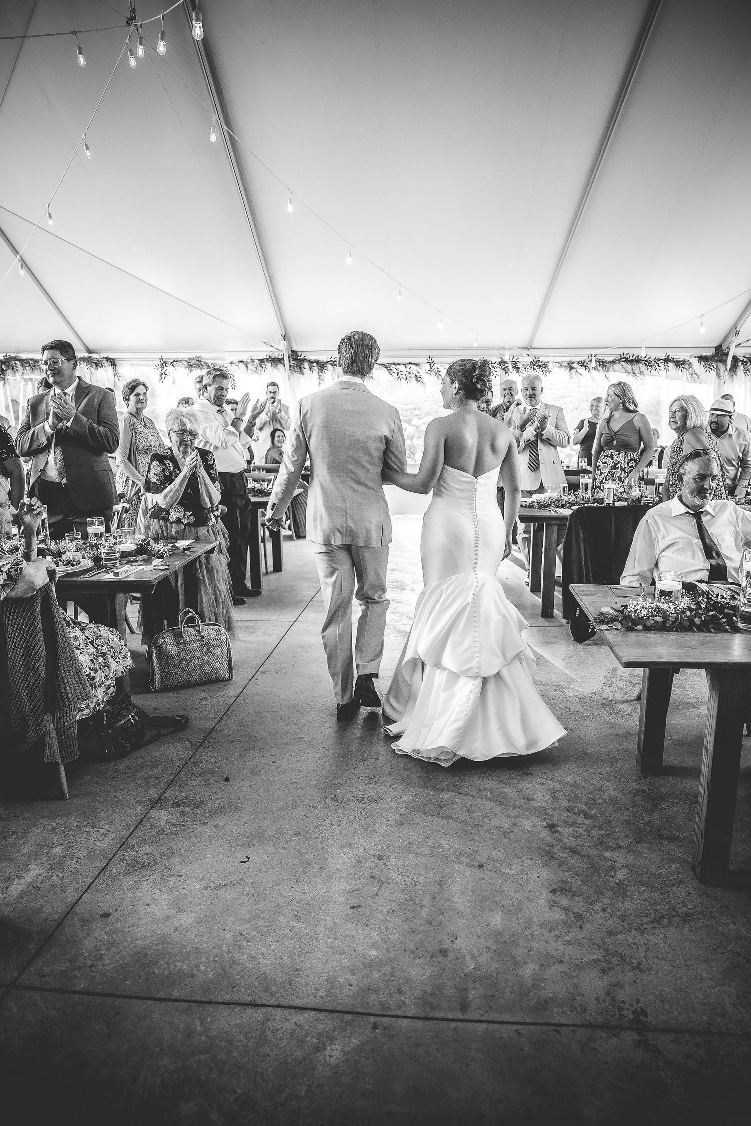 Wedding reception candid moments in black and white under an elegant tent setting.