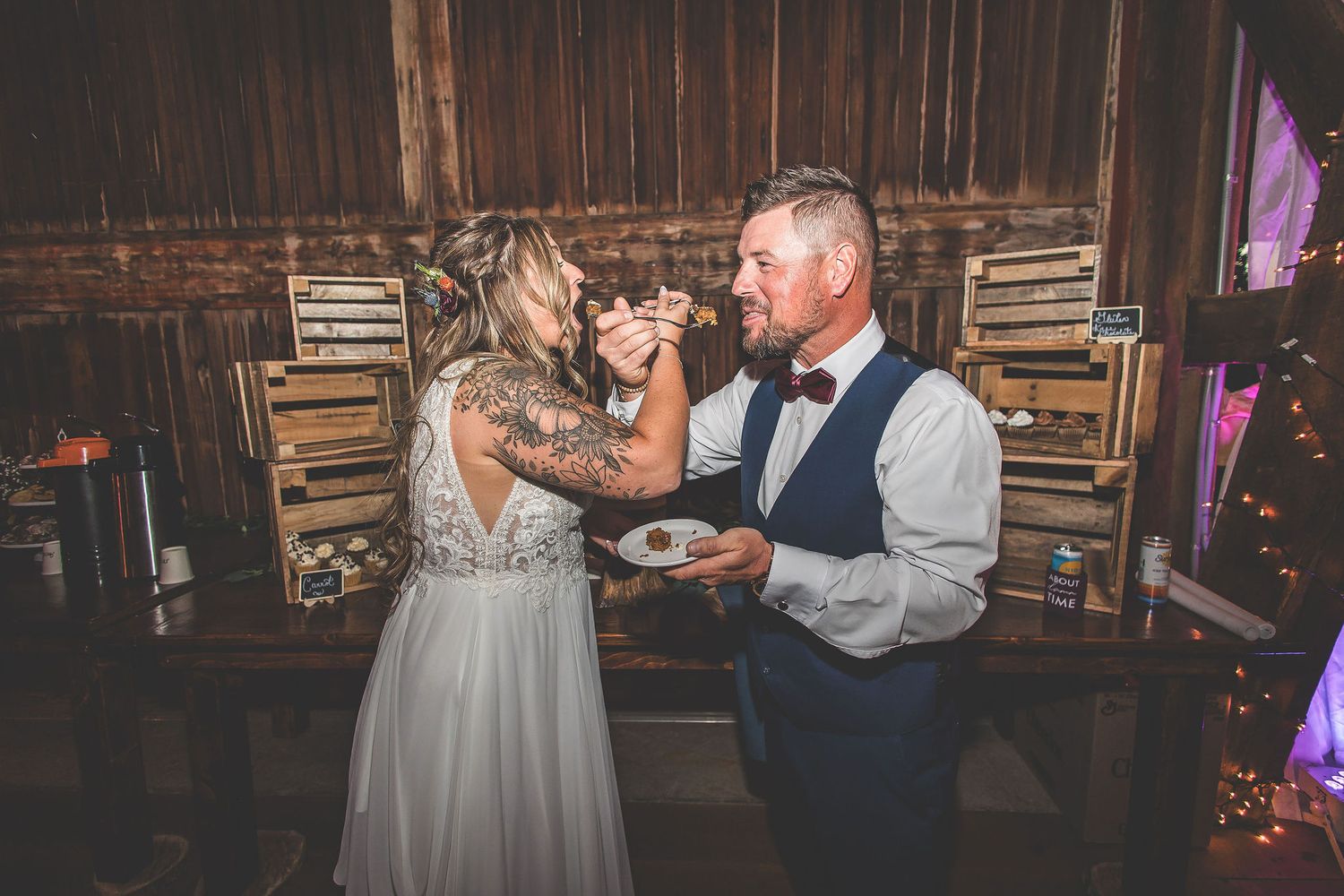 Intimate moments captured during wedding reception in a dimly lit rustic barn setting.