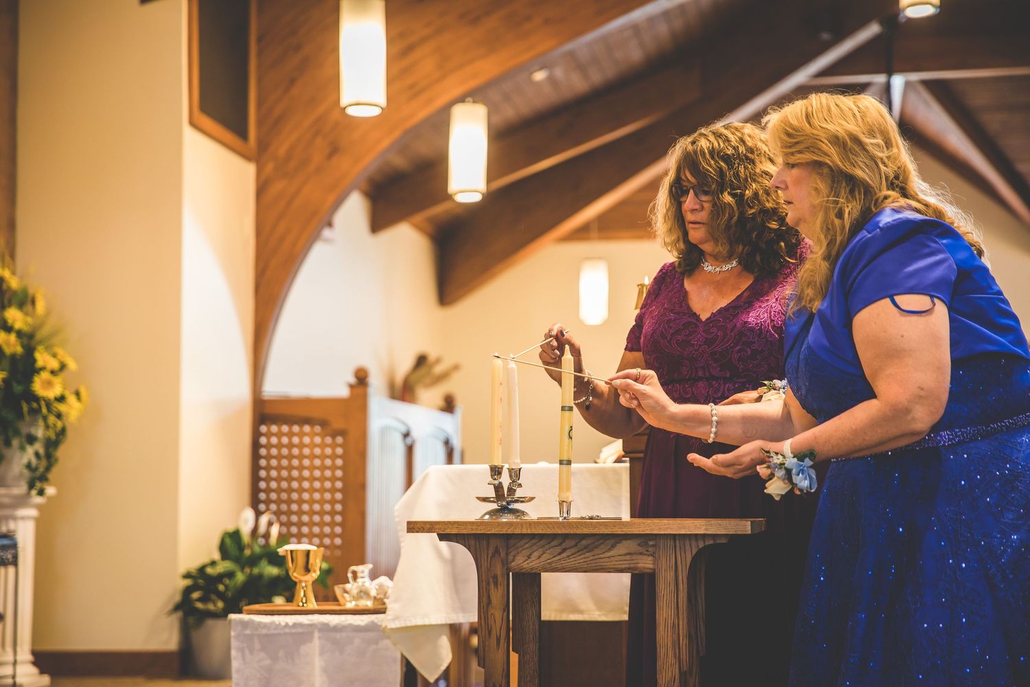 Wedding ceremony in a church with wooden beams and stained glass windows.