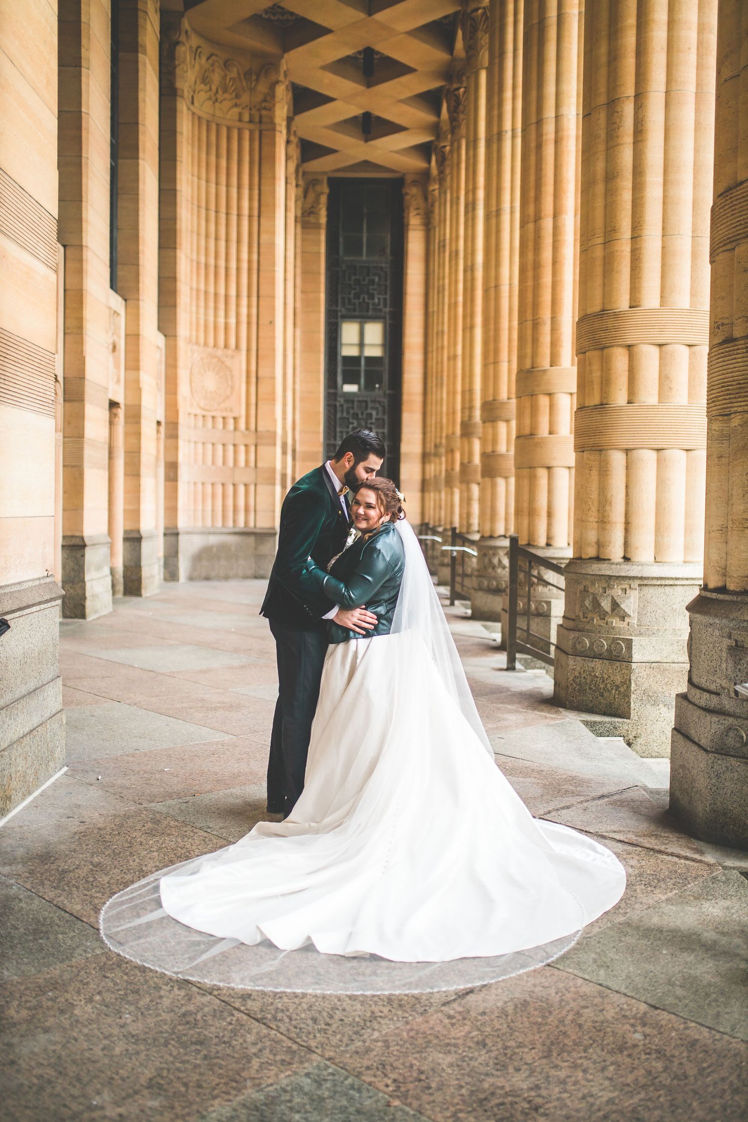 Wedding couple shares intimate moments under historic columned architecture.