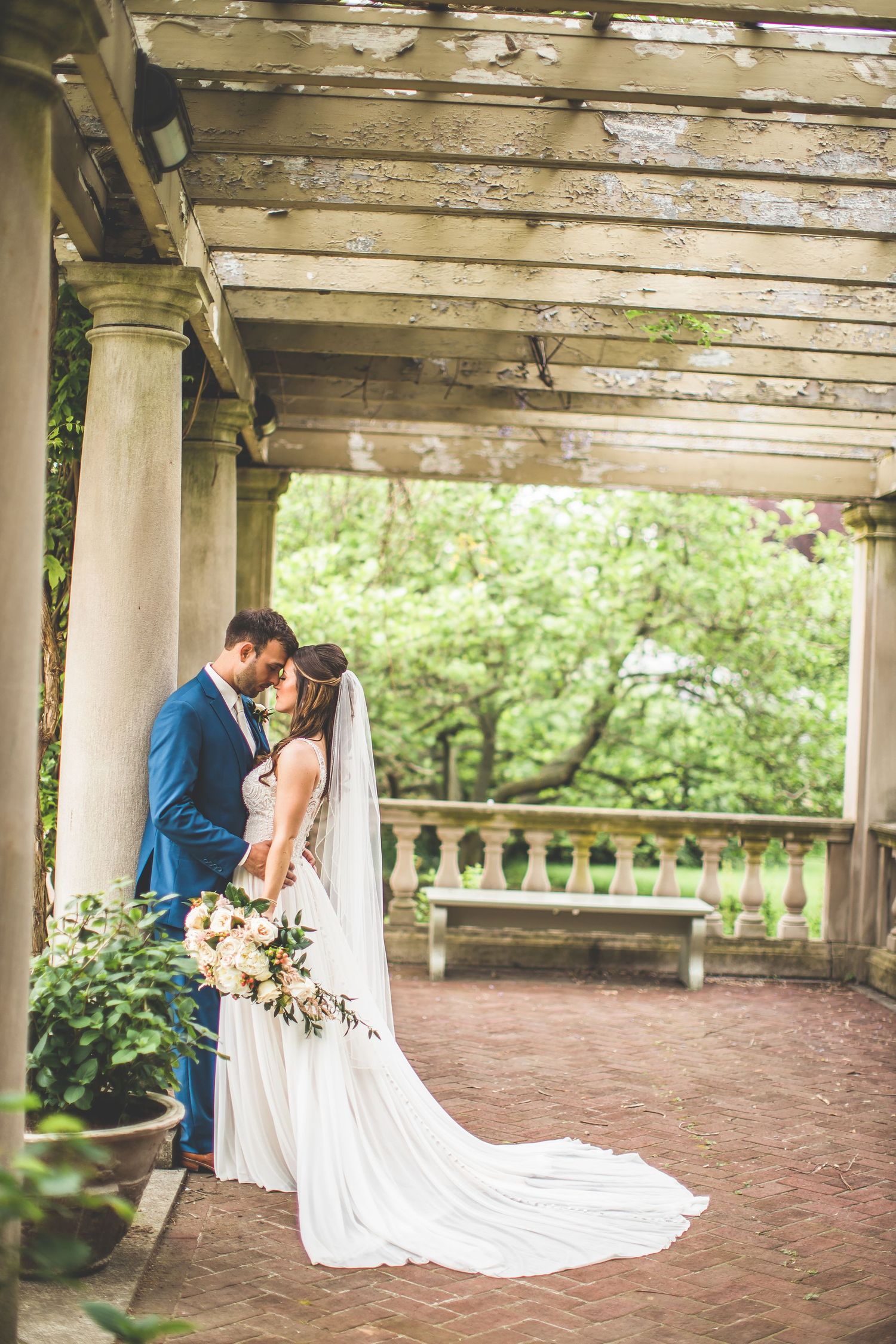Romantic wedding photos under rustic wooden pergola with brick floor.