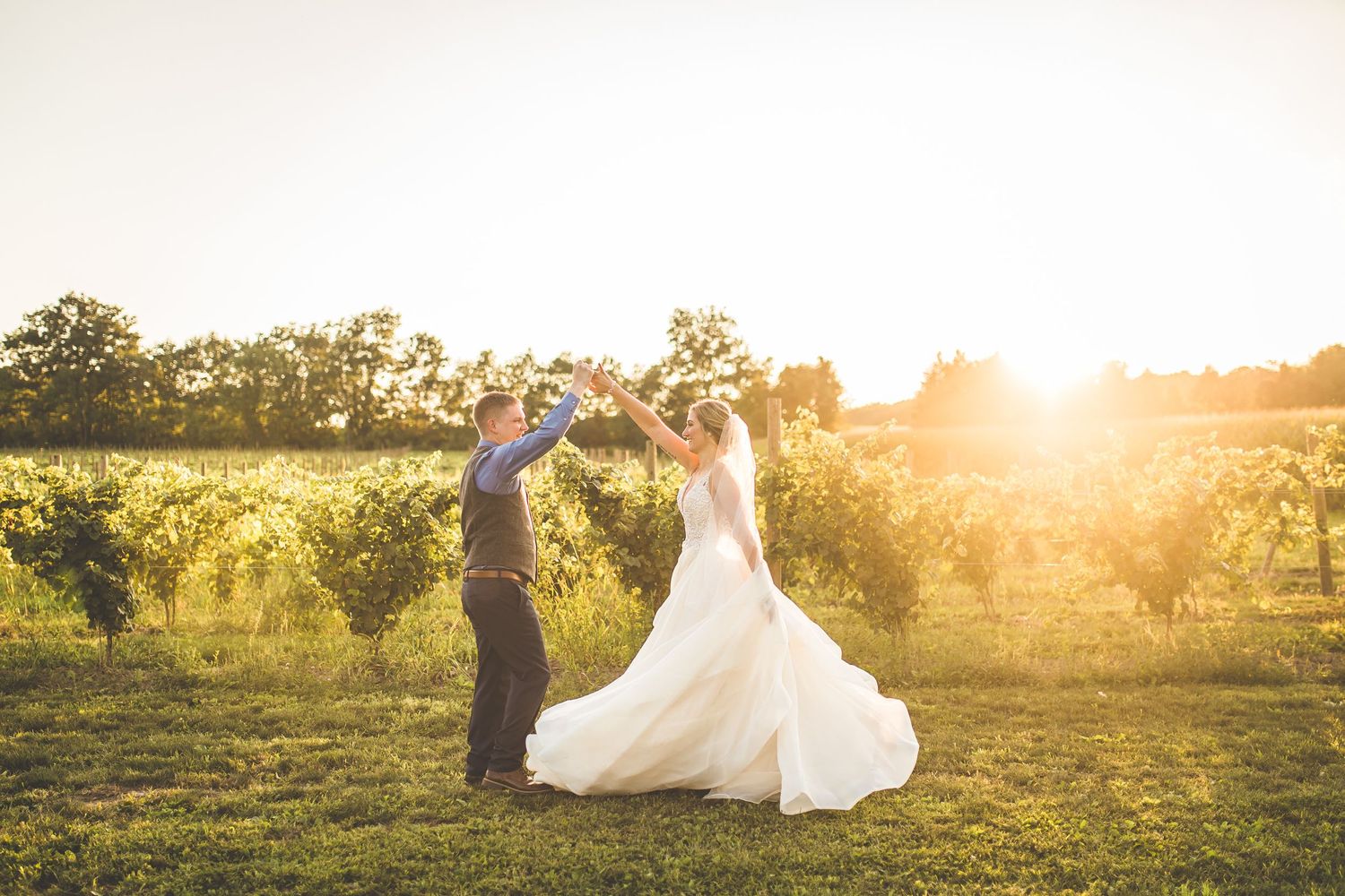Golden hour wedding portraits in a sunlit meadow with dramatic lighting.