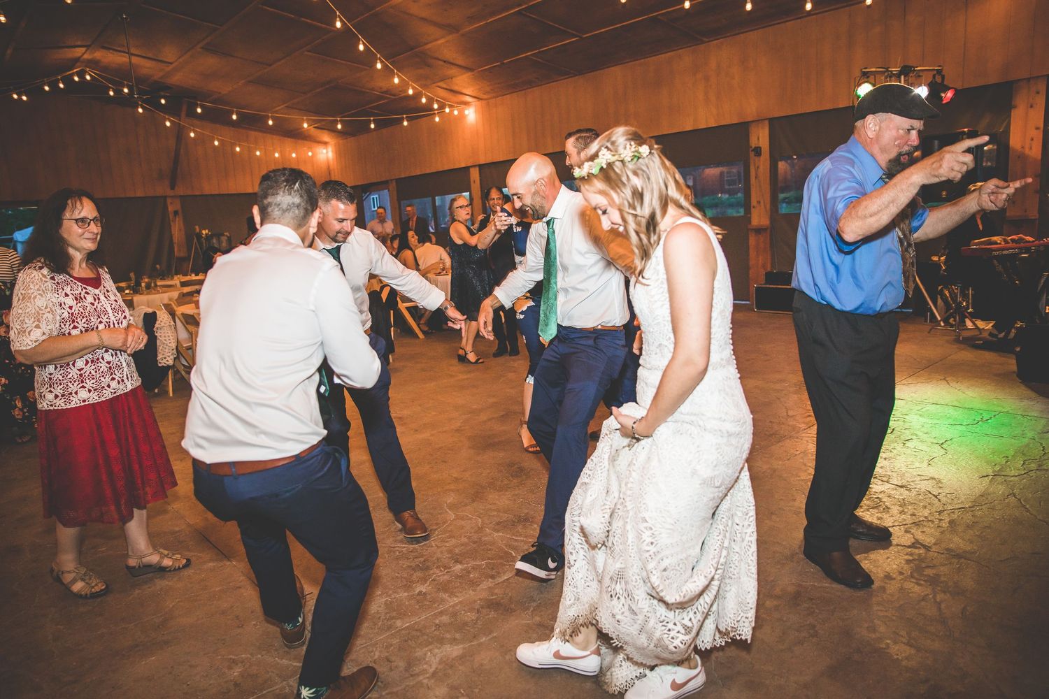 Wedding reception dance floor filled with guests celebrating under string lights.
