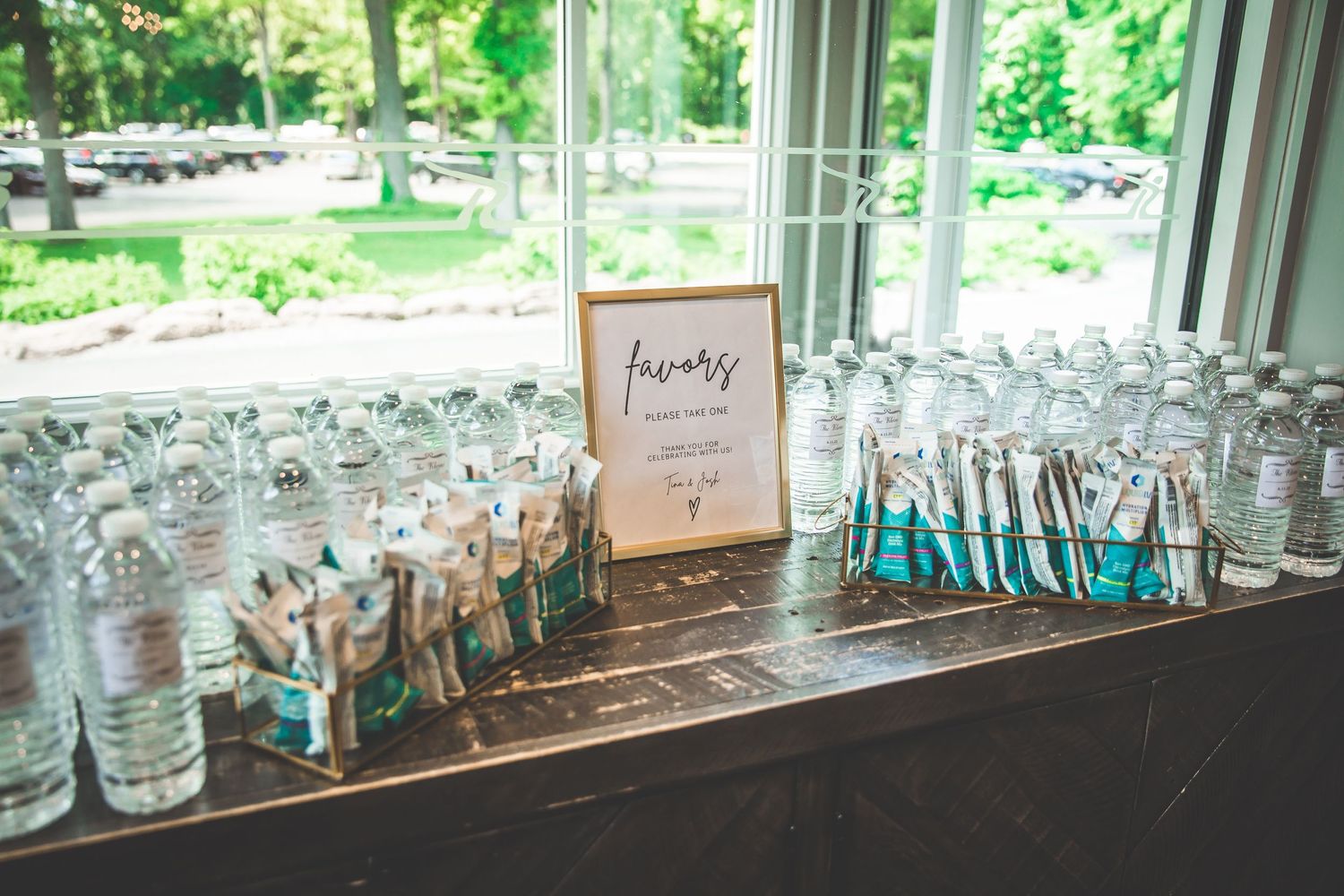 Row of glass jars and wedding favors displayed along a sunlit windowsill.