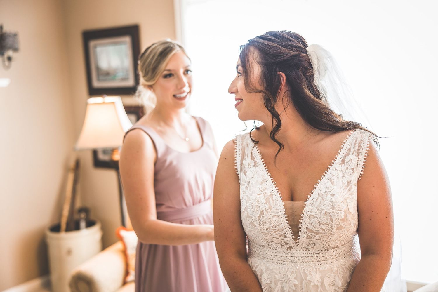 Wedding party members share joyful moments while getting ready in a sunlit room.