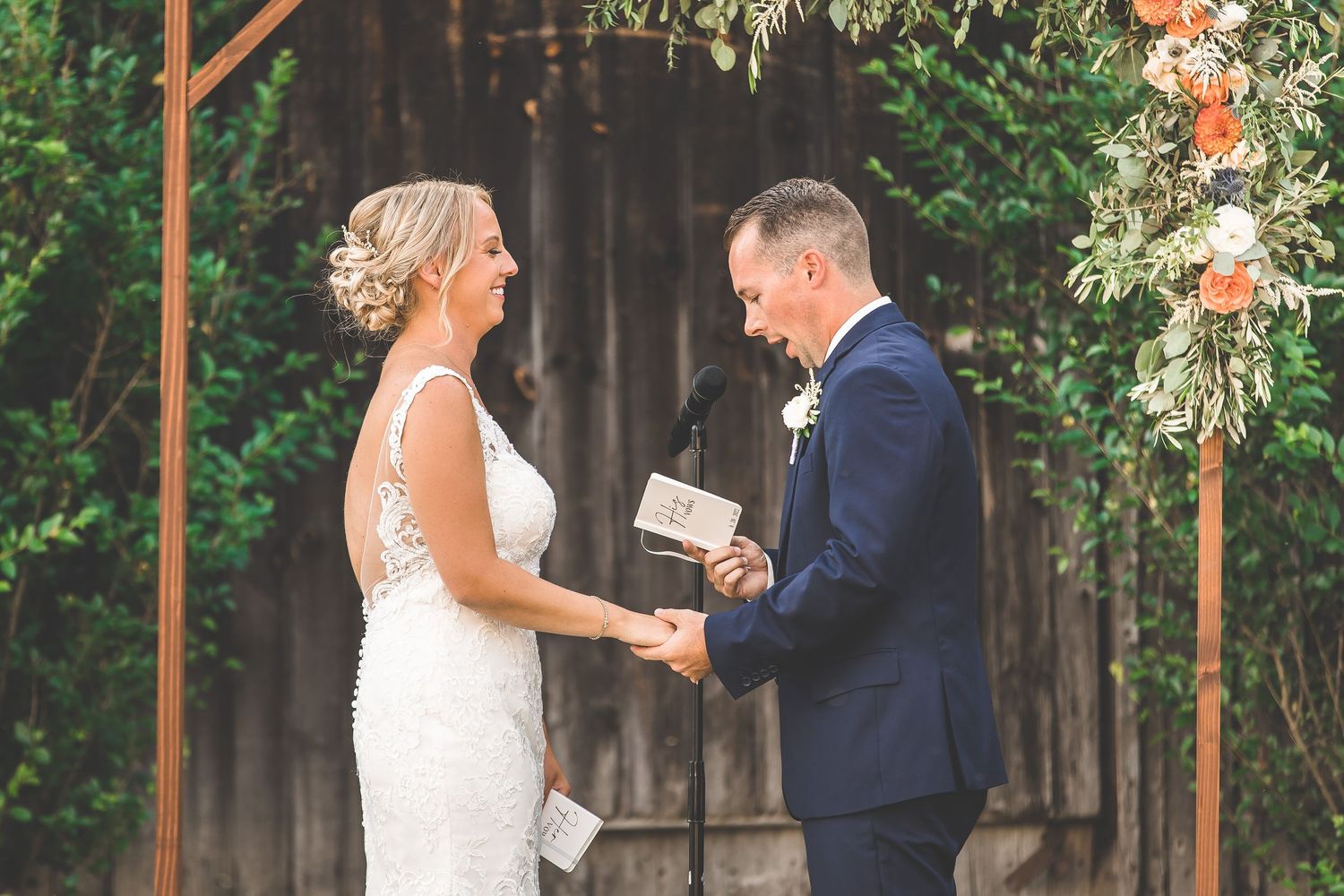 Intimate wedding ceremony moment under a wooden arch with floral decor.