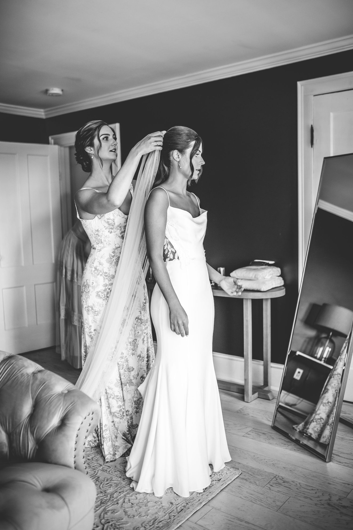 Black and white photo of wedding dress preparations in a sunlit room.