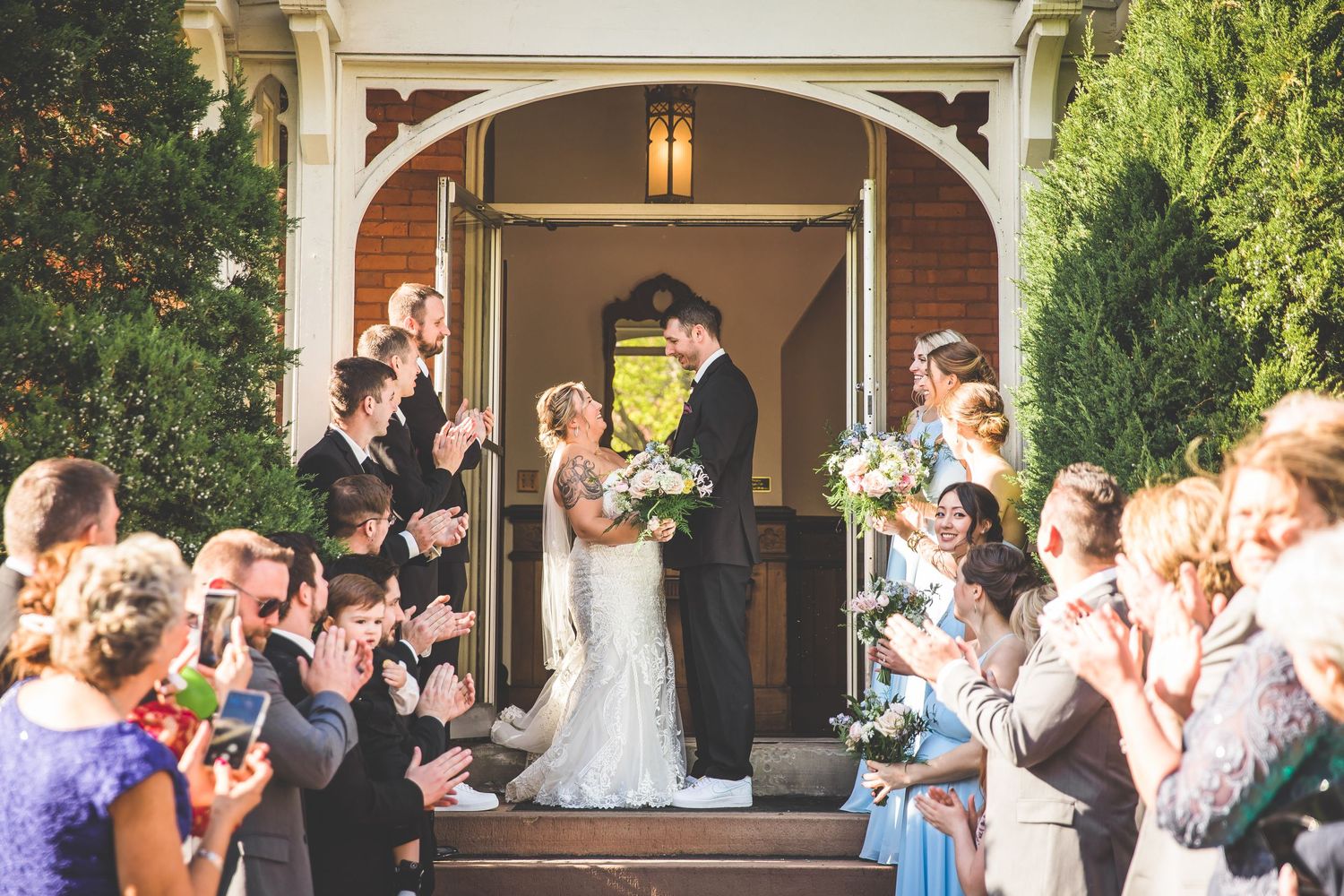 Outdoor wedding reception scene with guests celebrating under an elegant archway.