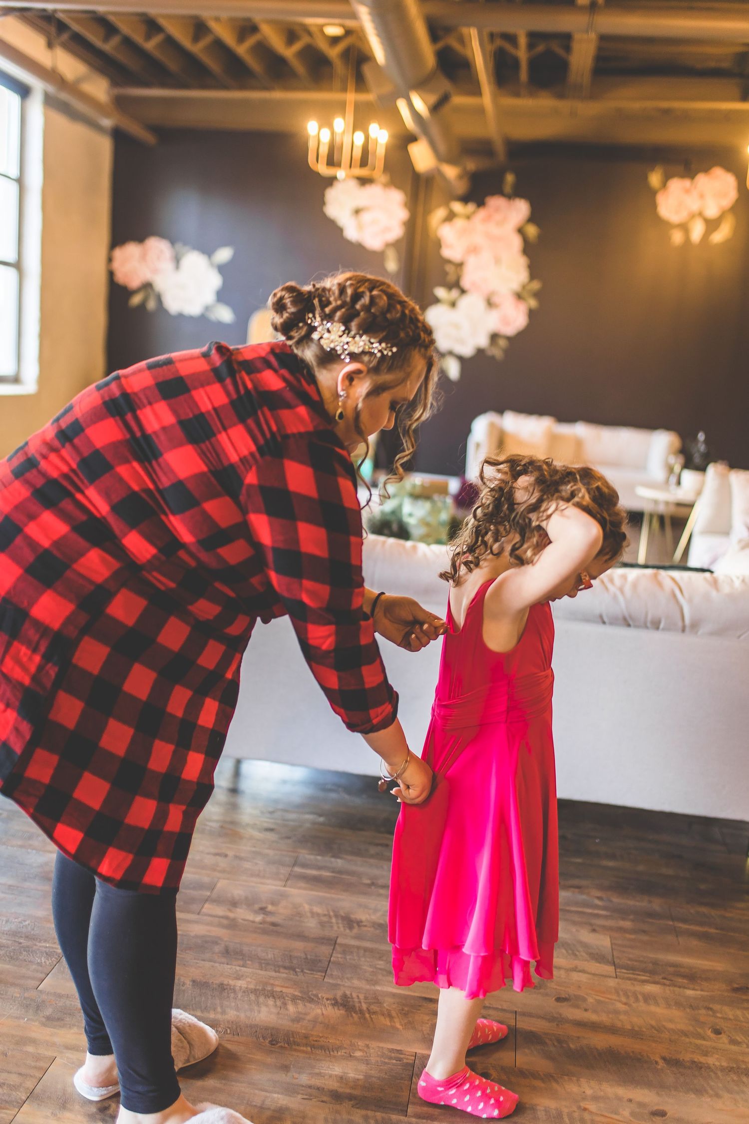 Person in buffalo plaid shirt bending down to interact with small figure in bright pink dress.