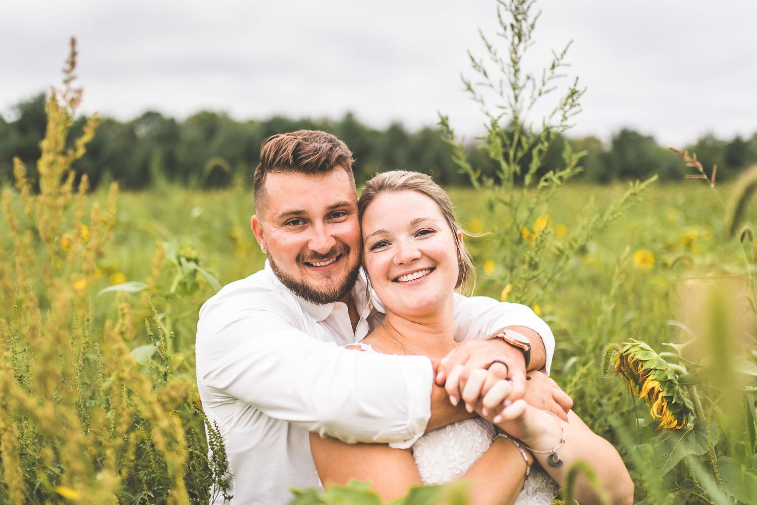 Happy couple embracing in a field of blooming summer flowers.