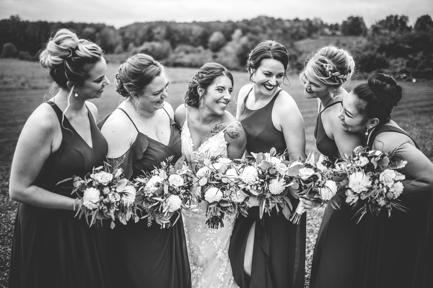 Wedding party members sharing joyful moments and laughter together outdoors.