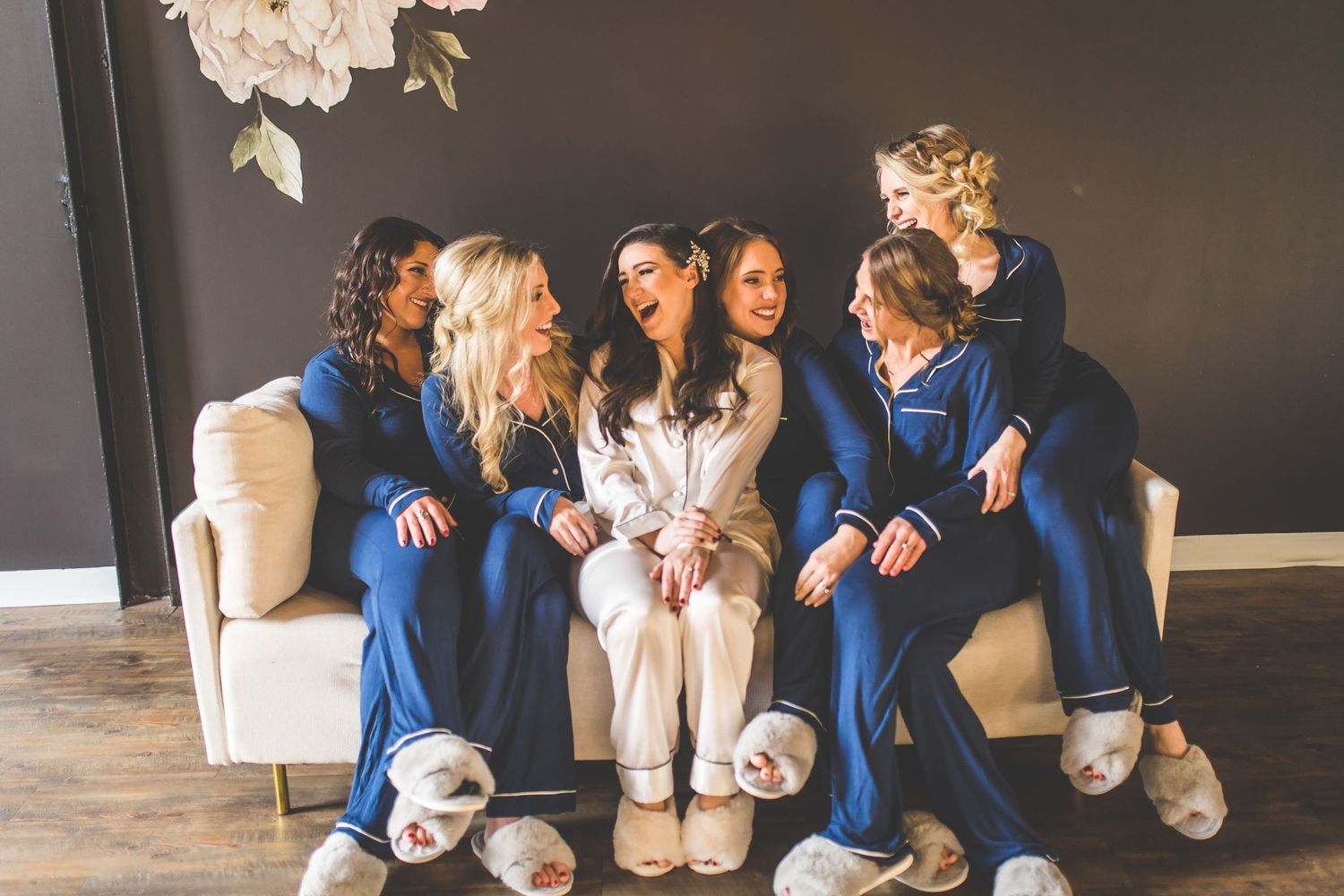Bridesmaids in navy blue dresses share candid moments during wedding preparations.