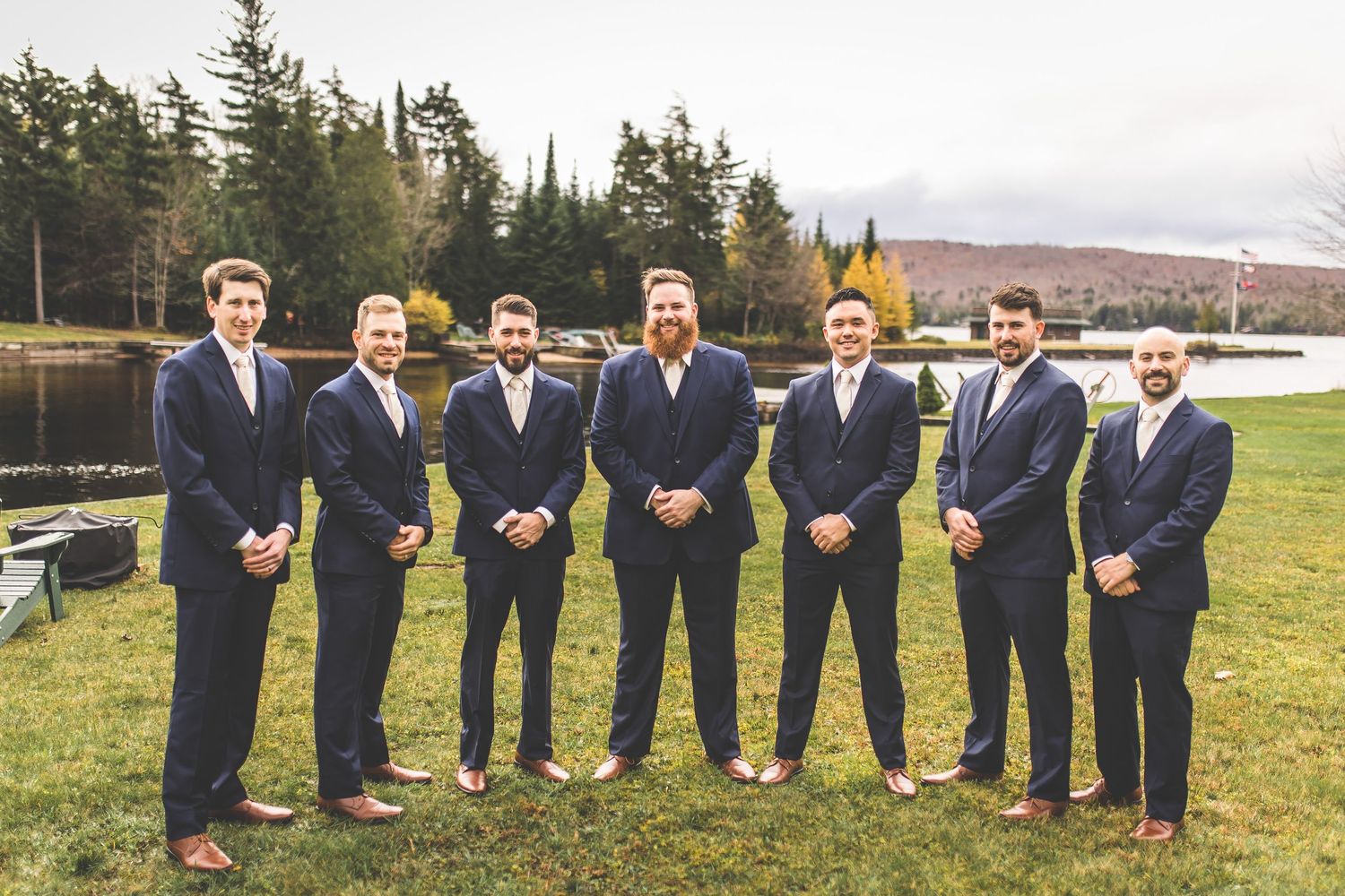 Groomsmen in navy suits posing outdoors against a scenic mountain landscape.