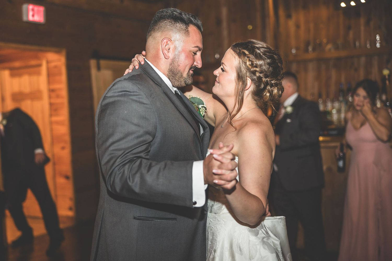 Couples dancing at wedding reception in rustic barn venue with romantic lighting.