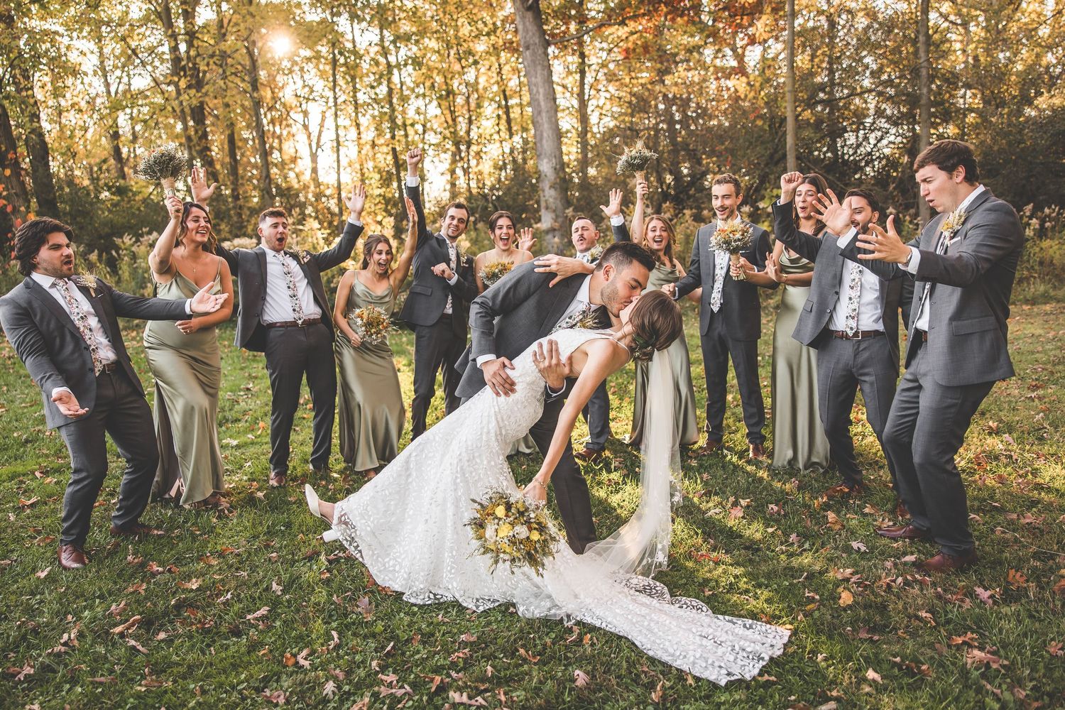 Wedding celebration group shot in scenic fall forest setting.