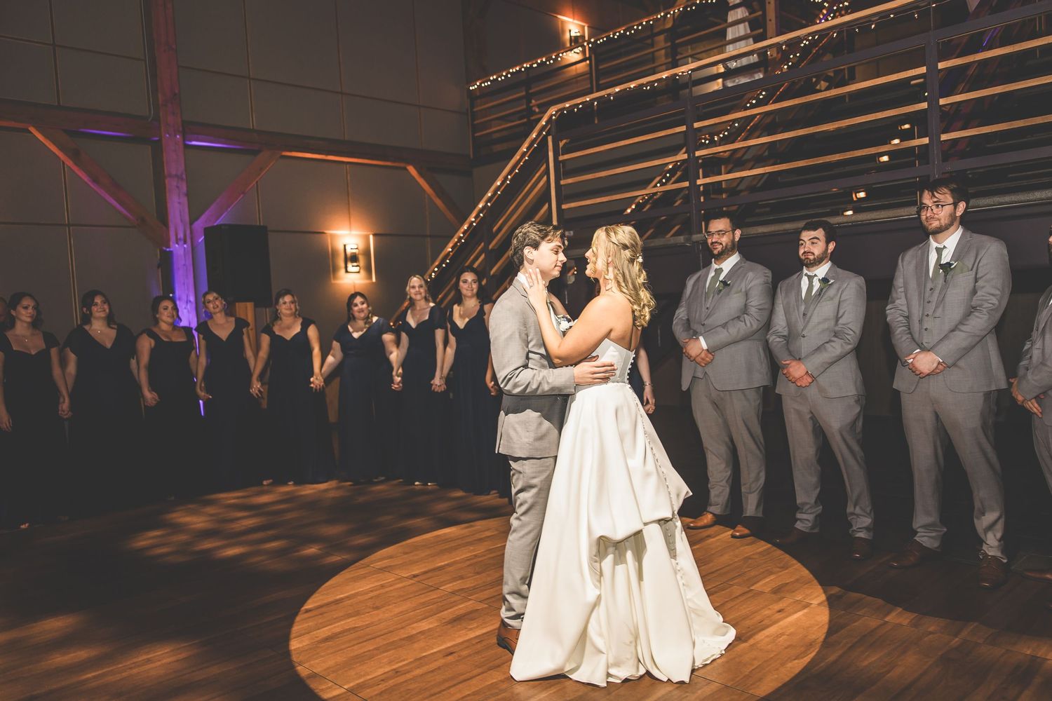 Wedding reception dance floor with romantic lighting and wooden architectural details.