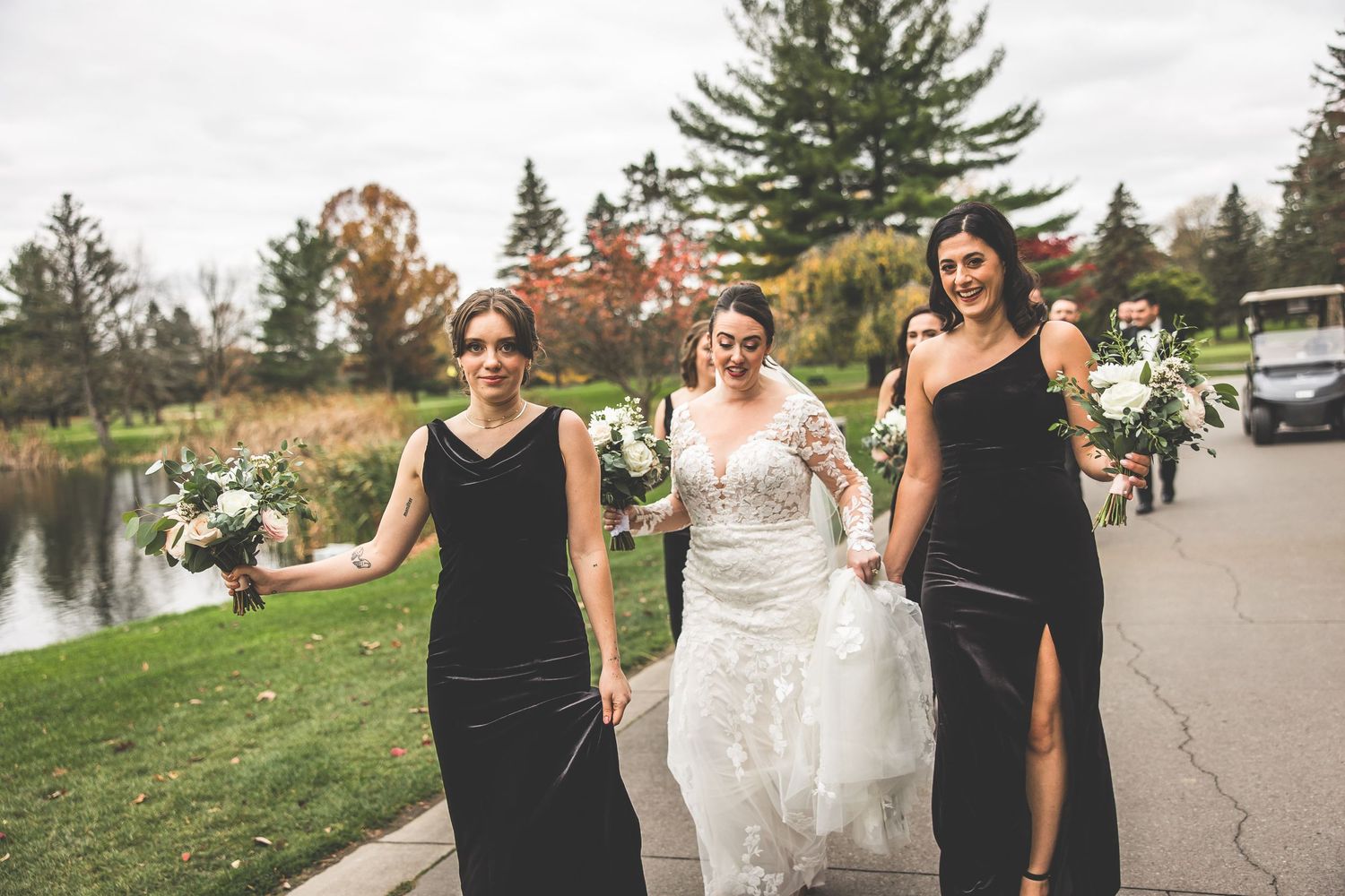 Wedding party walking together on paved path during autumn celebration.