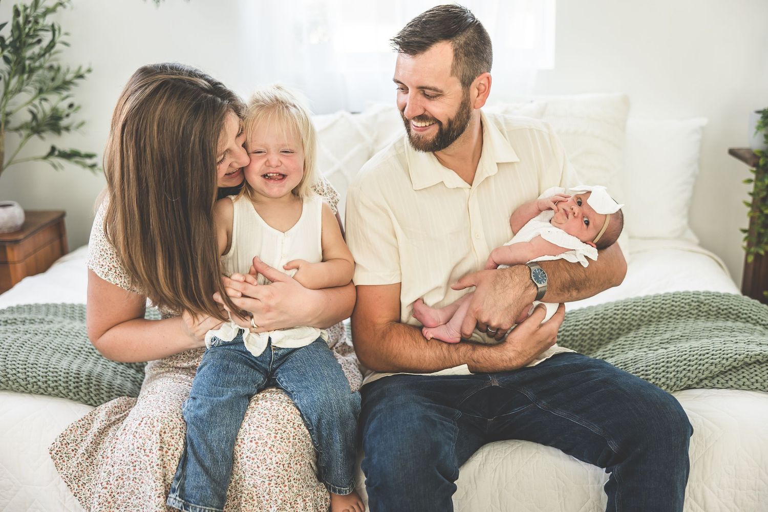 A family shares joyful moments together on a light gray couch in a bright living room.