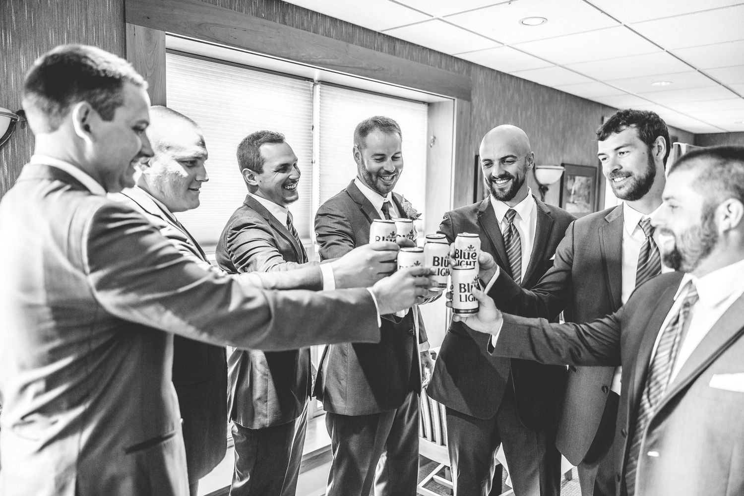 Wedding party members sharing celebratory drinks and toasts in an indoor venue.