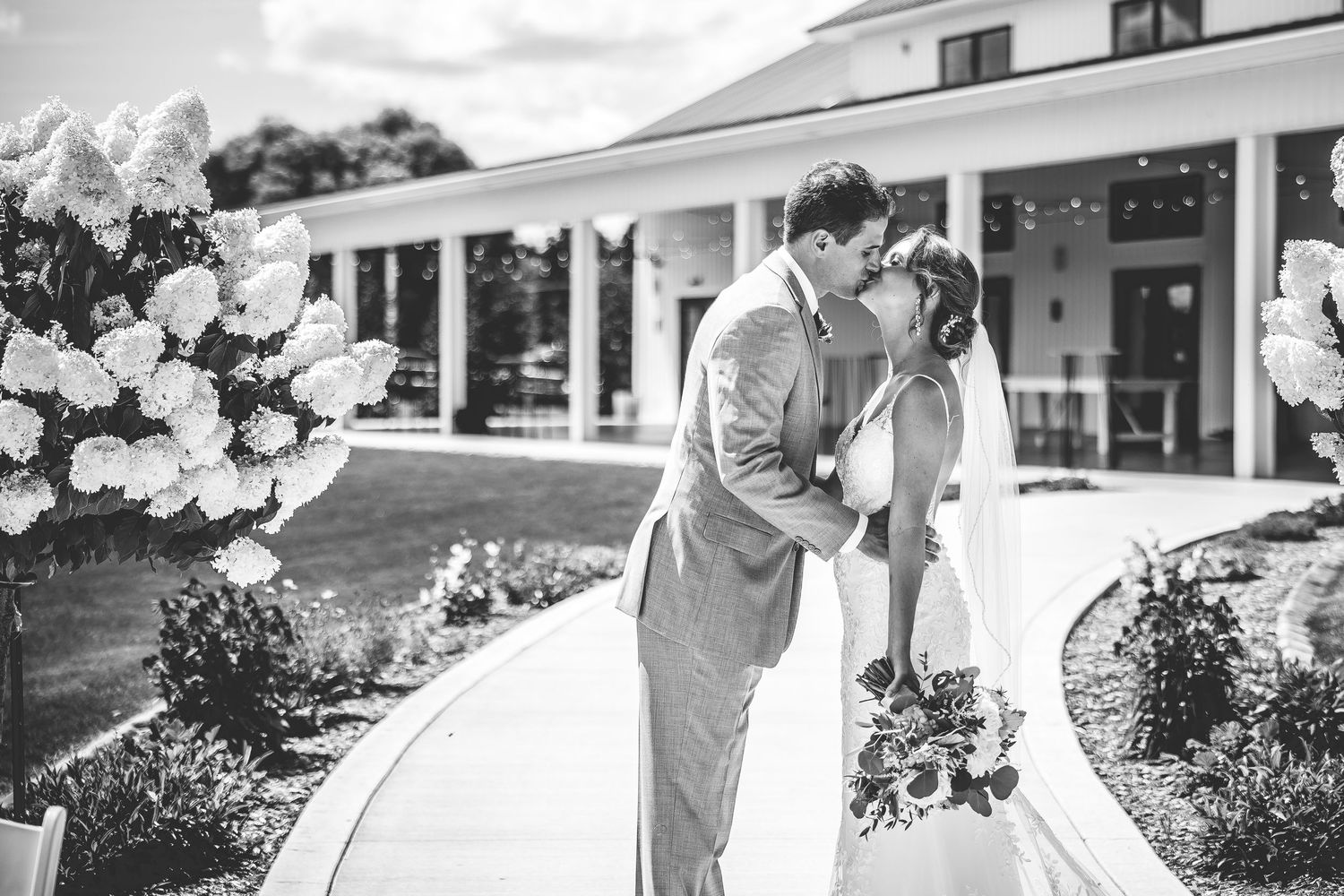 Romantic wedding couple embracing in front of a modern white building.