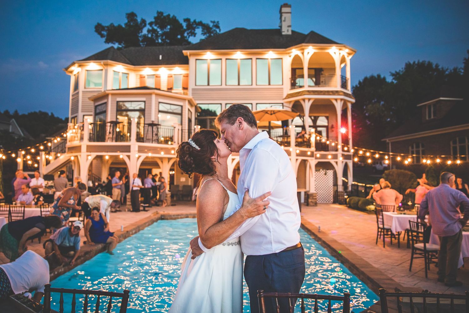 Elegant wedding venue at dusk with illuminated pool and string lights creating ambient atmosphere.