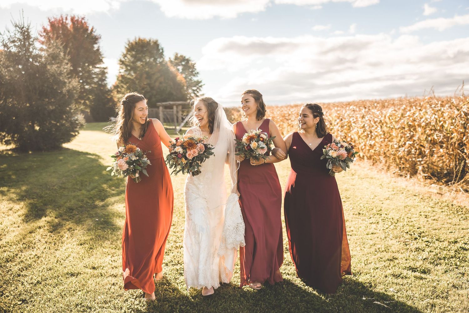 Wedding party silhouetted against golden sunset in open field.