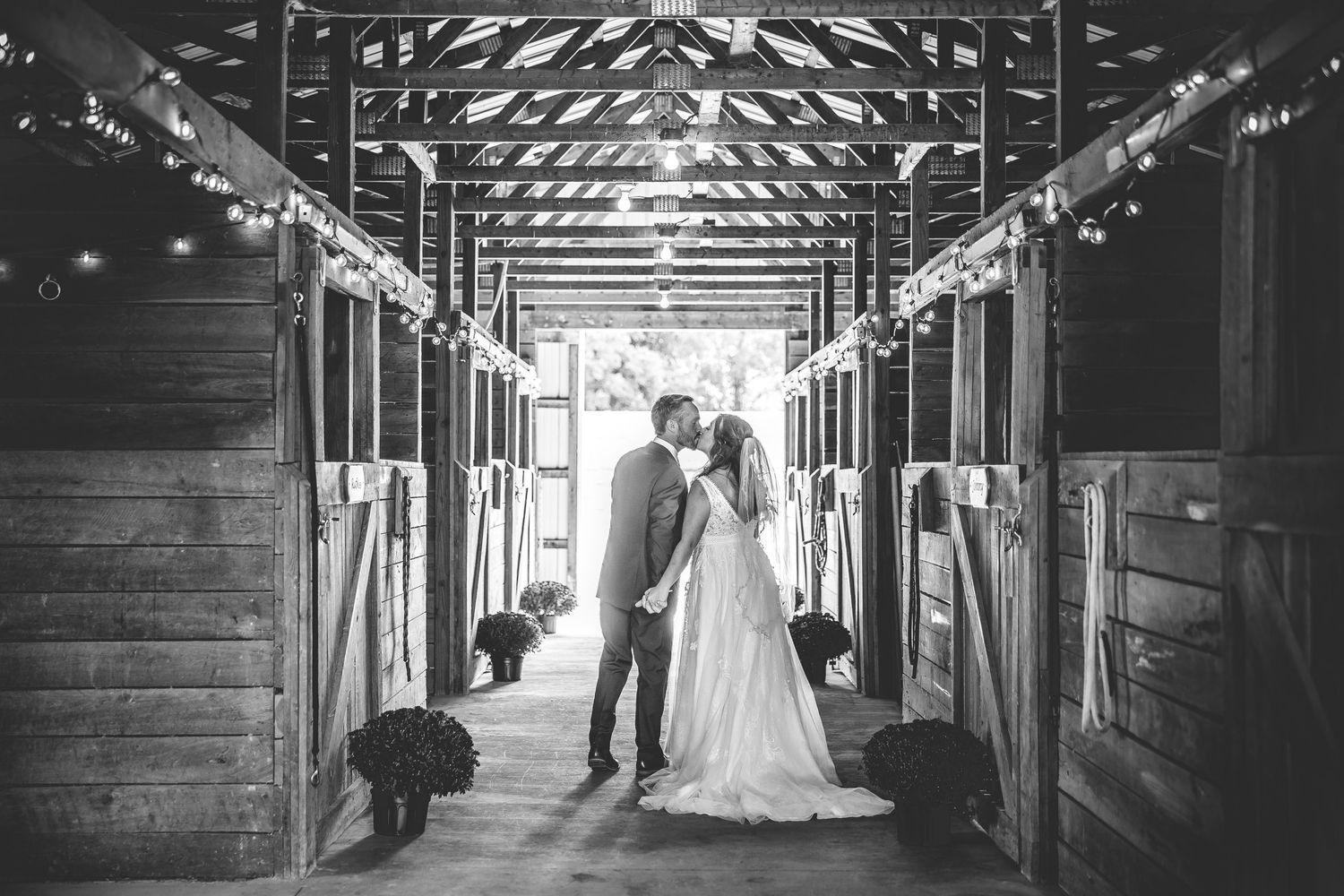Black and white wedding photos showcase rustic barn venue with dramatic lighting.