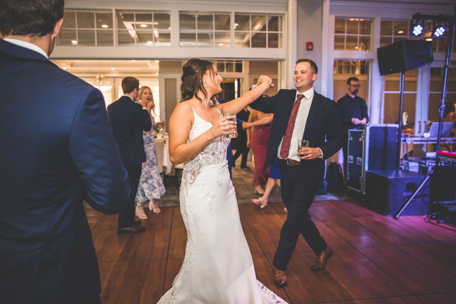 Evening wedding reception shows dance floor with blue mood lighting and dancing guests.