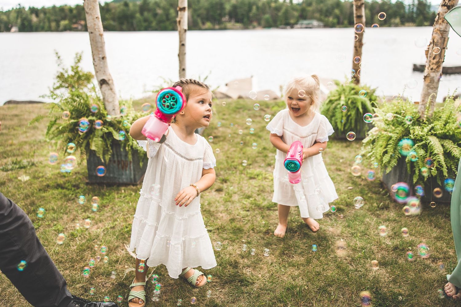 Children play with bubbles in a grassy outdoor area during a summer celebration.