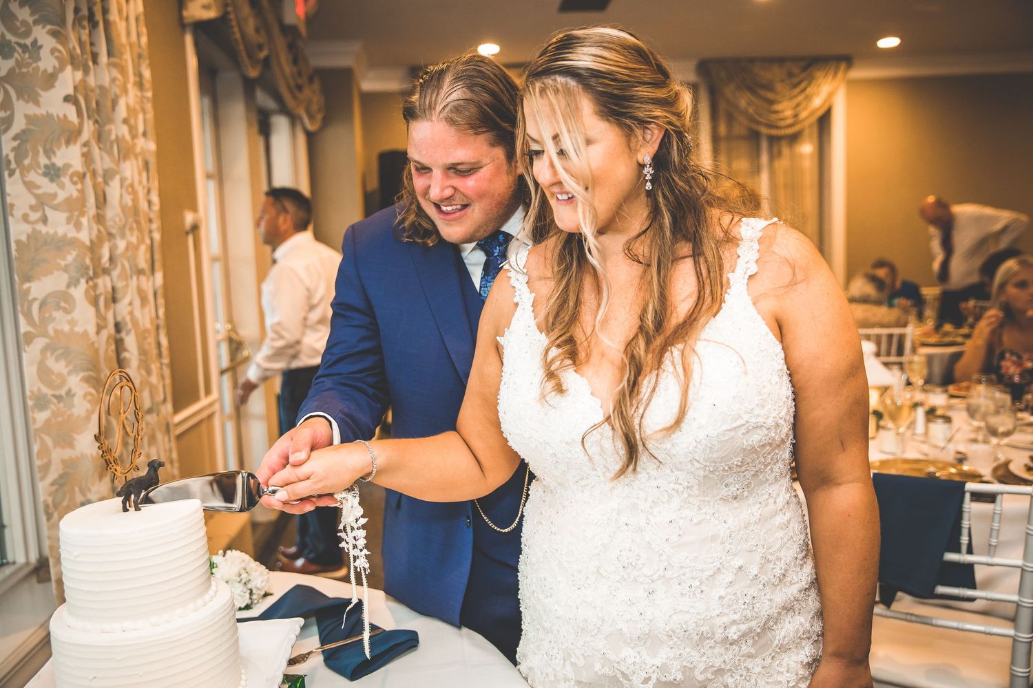 A wedding reception celebration with guests dining under warm indoor lighting.
