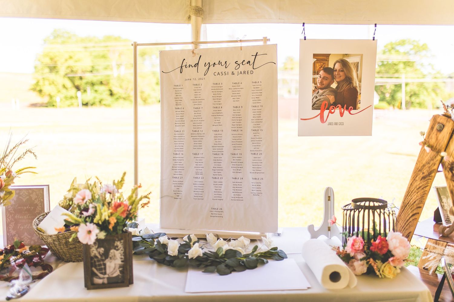 Wedding reception seating chart and signage displayed on white backdrop.
