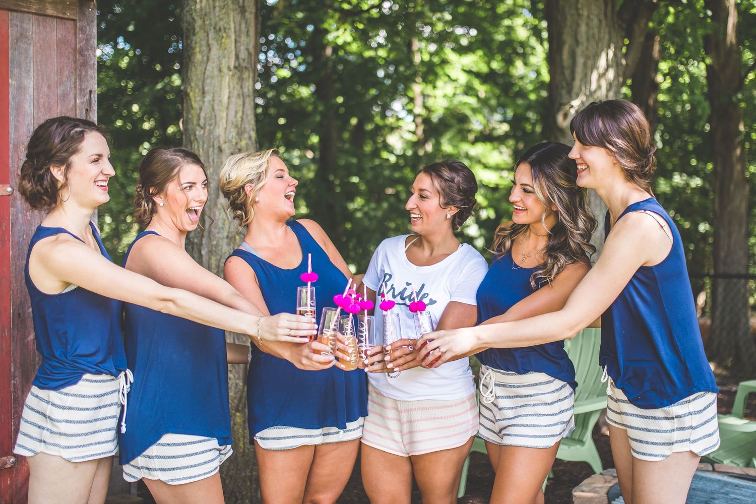 Wedding party in blue and white outfits laughing together outdoors.