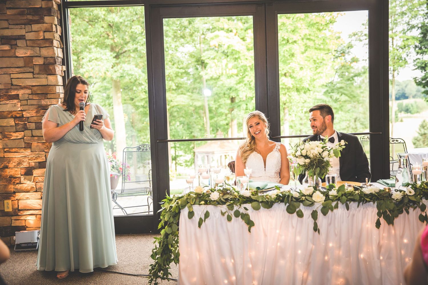 A wedding speech being delivered at a reception with fairy light backdrop and floral decorations.