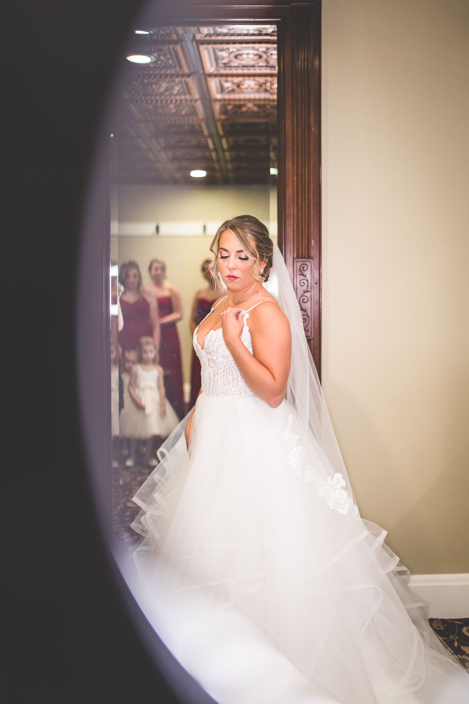 An artistic mirror reflection of a bride in her wedding gown getting ready.