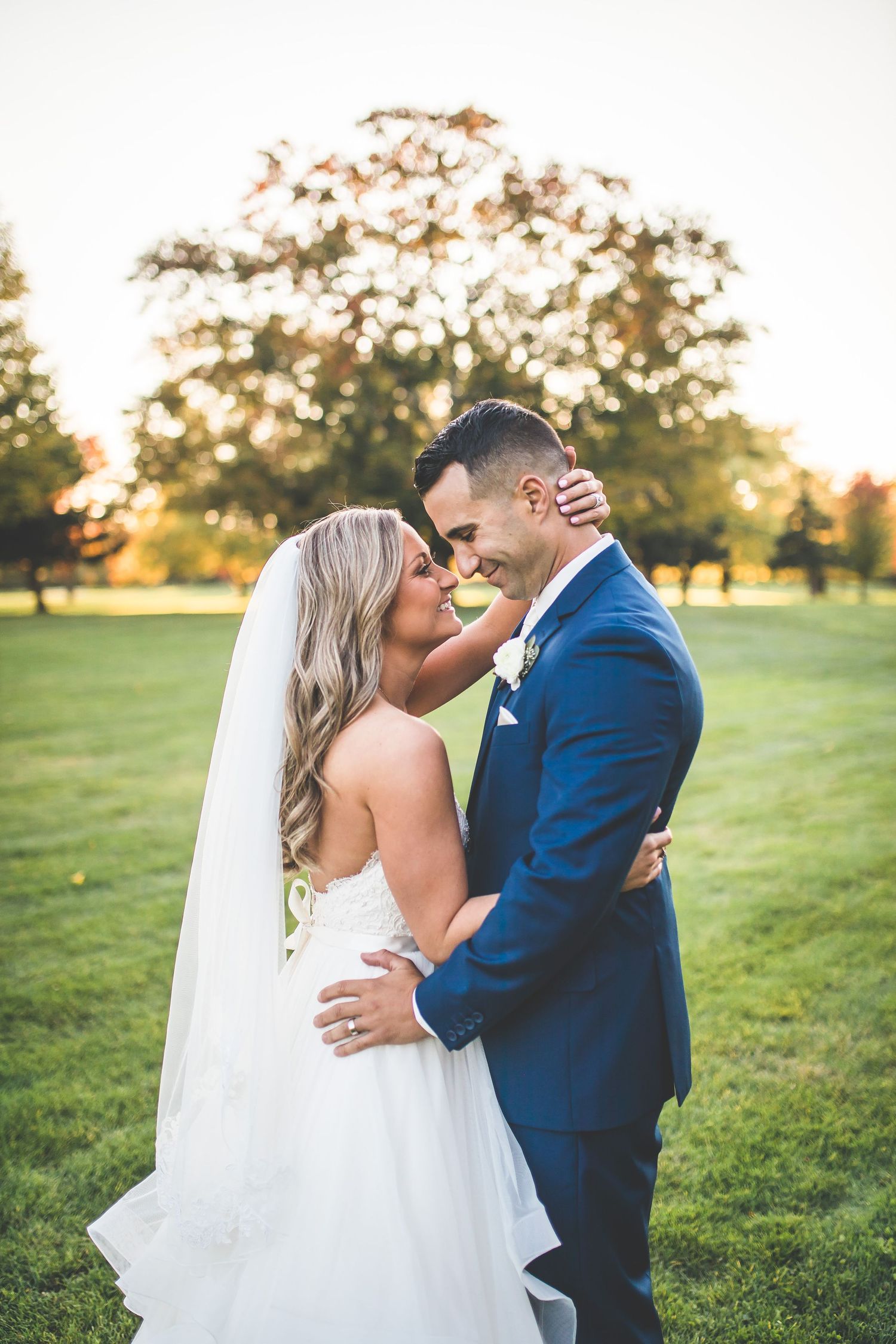 Sunset wedding photos in a grassy field with golden hour lighting.