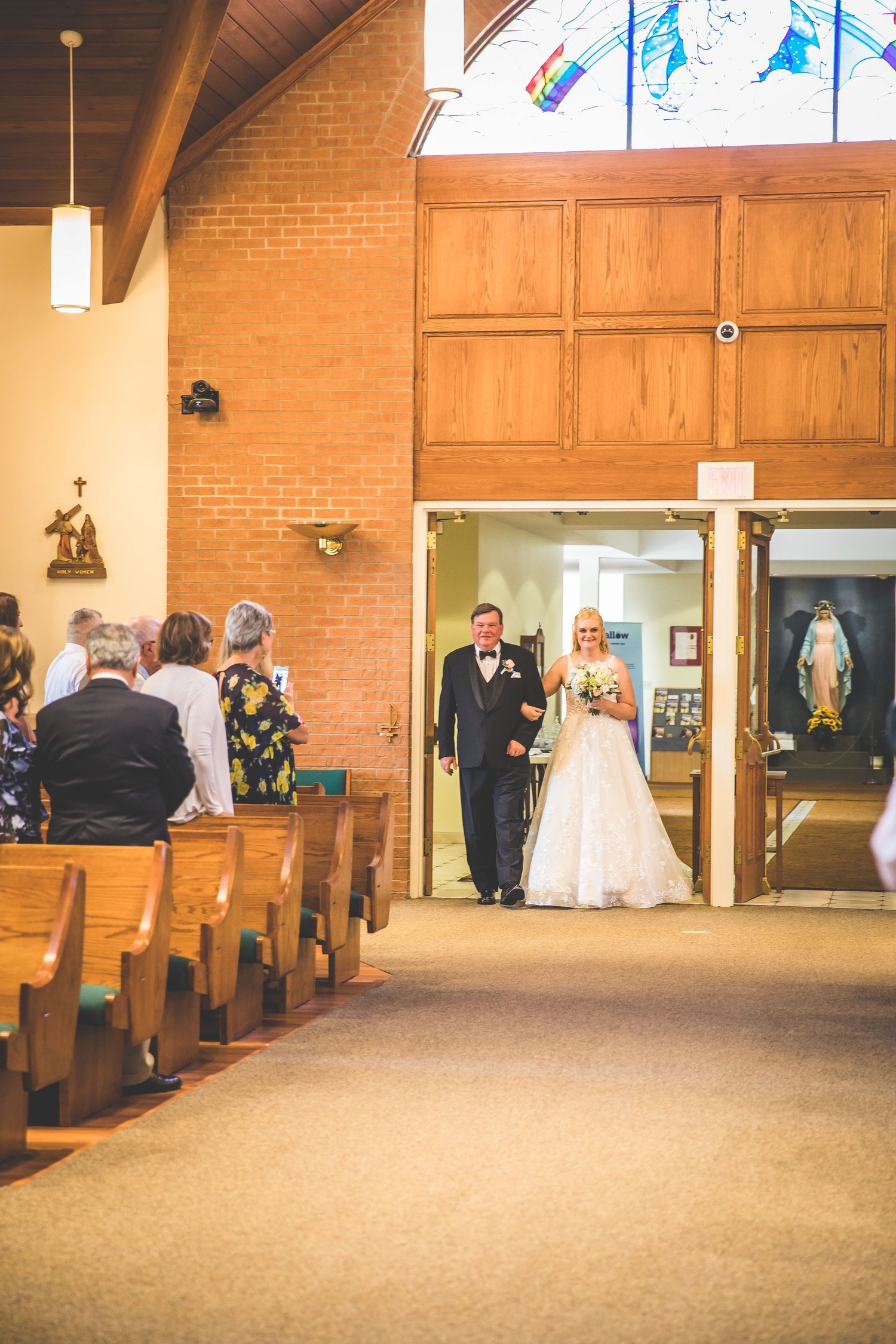 Wide view of church aisle and pews during wedding ceremony.