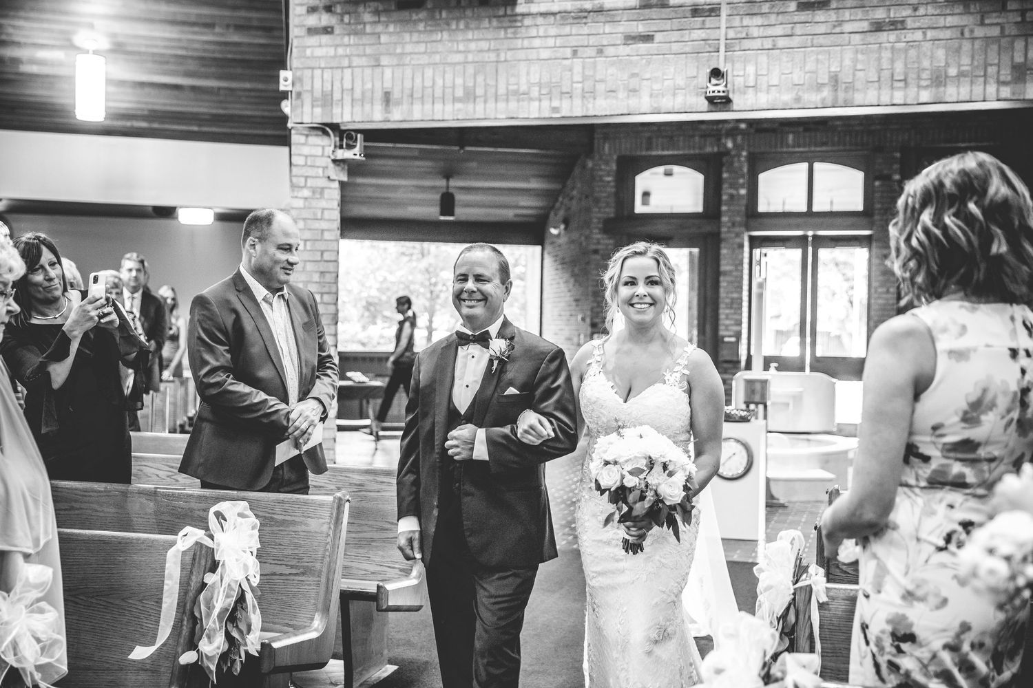 Black and white photo of wedding guests mingling in an elegant indoor reception space.