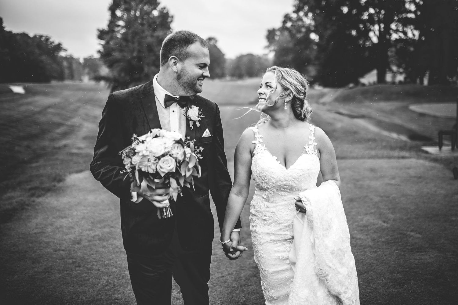 Black and white portrait of couple sharing intimate moment on golf course.