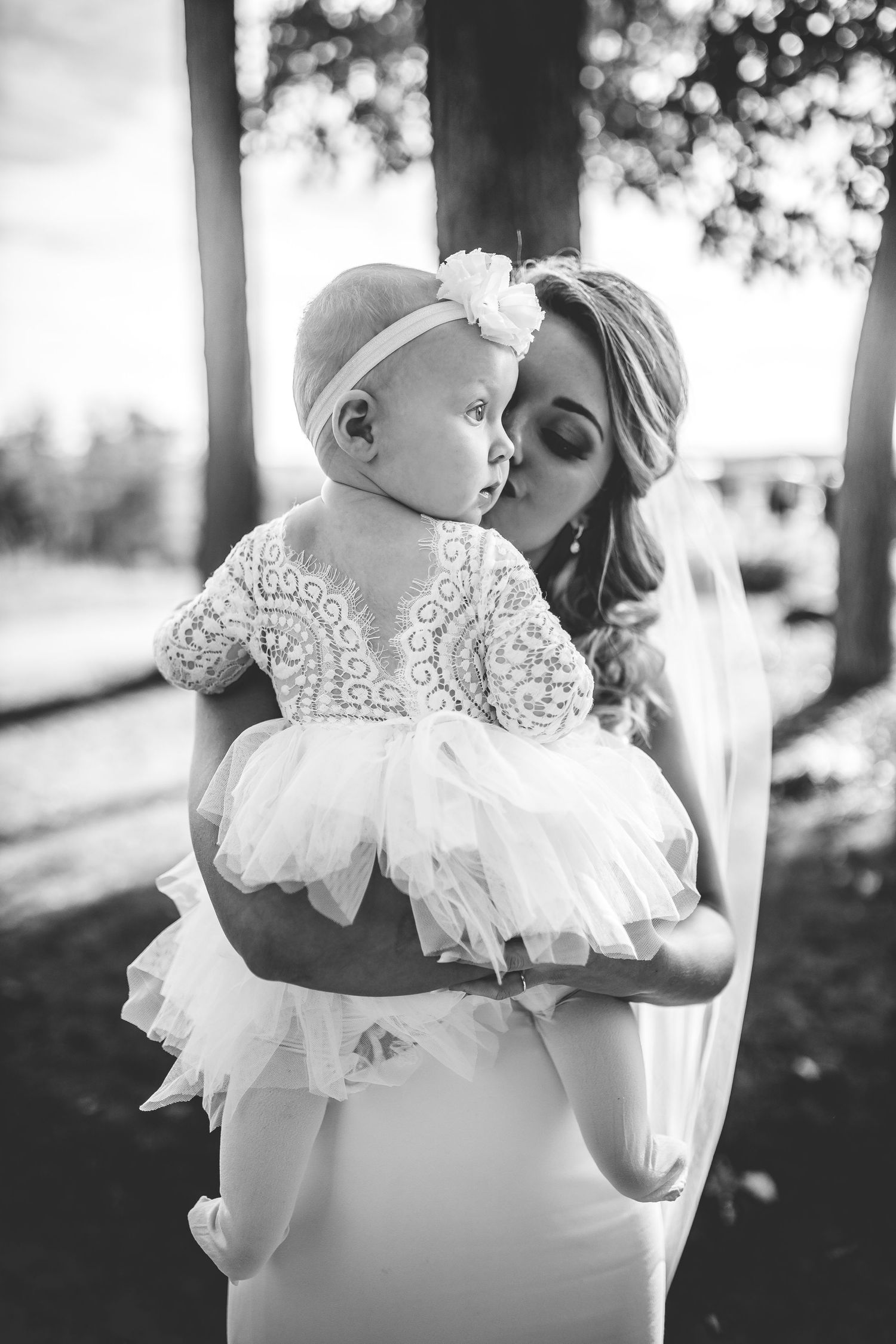 Black and white portrait of tender moment between mother and baby in lace dress.