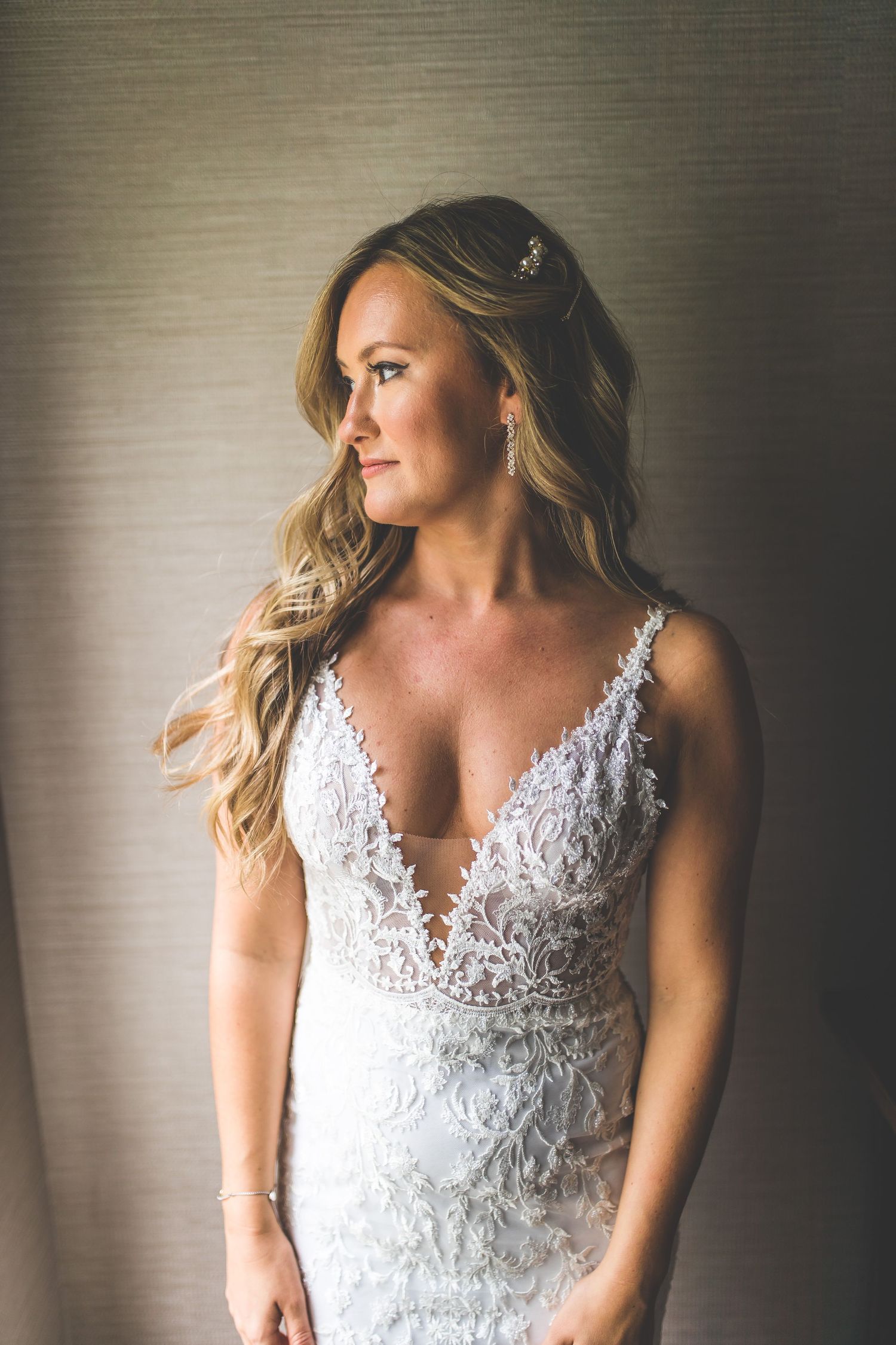 Elegant lace wedding dress photographed in dramatic lighting.