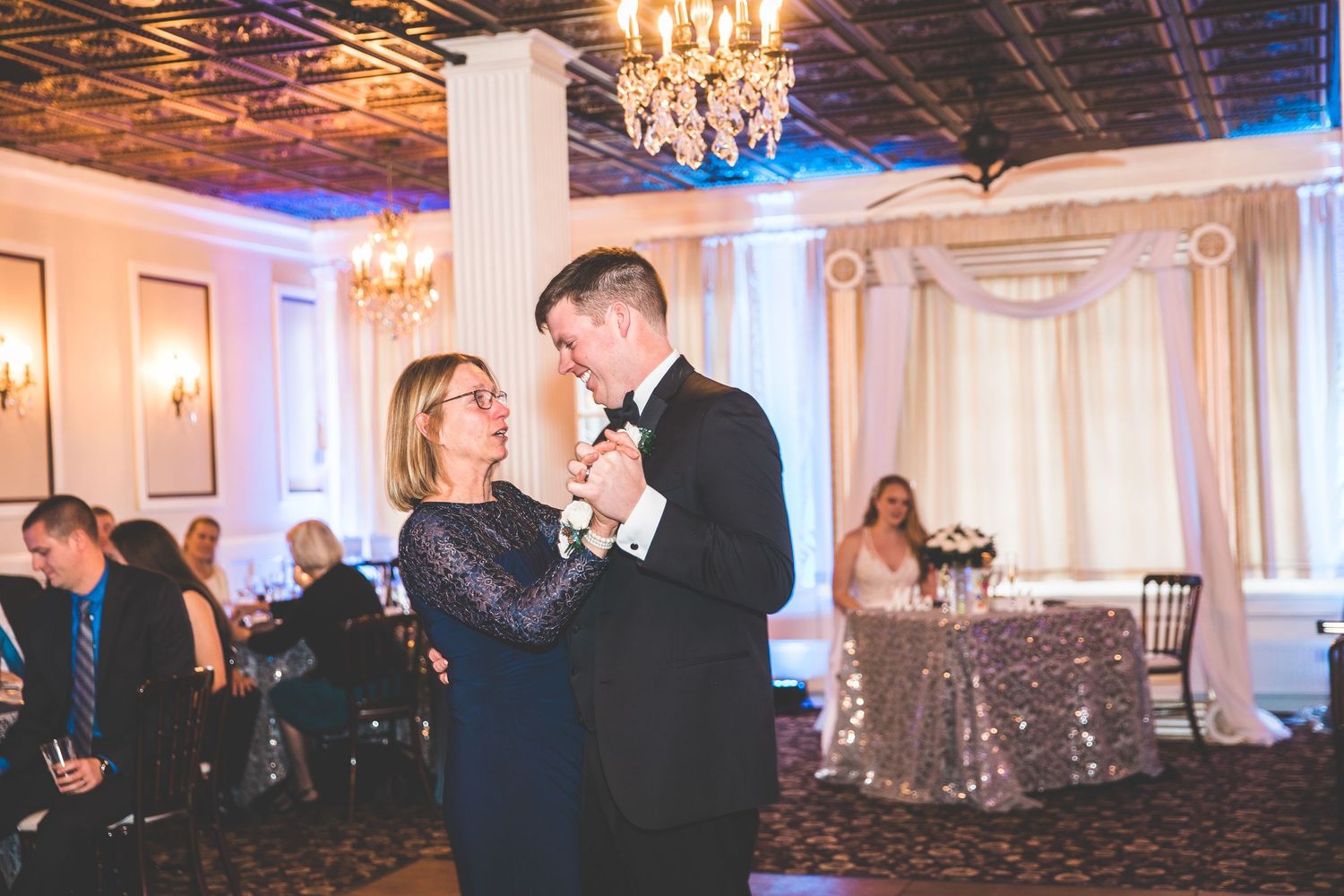 Spacious ballroom decorated with chandeliers and columns for an elegant wedding reception.