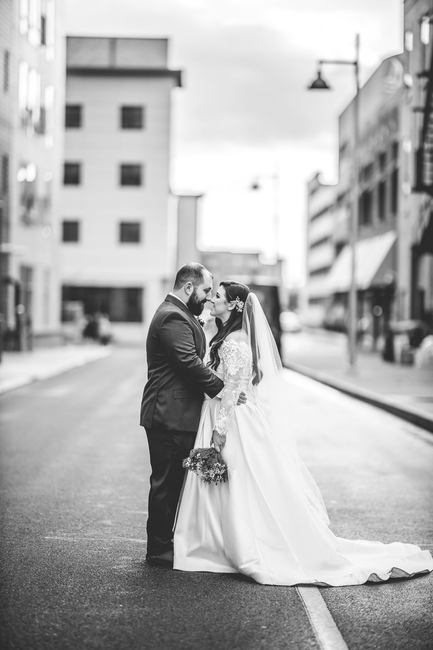 Black and white wedding photos showing romantic moments between newlyweds on an urban street.