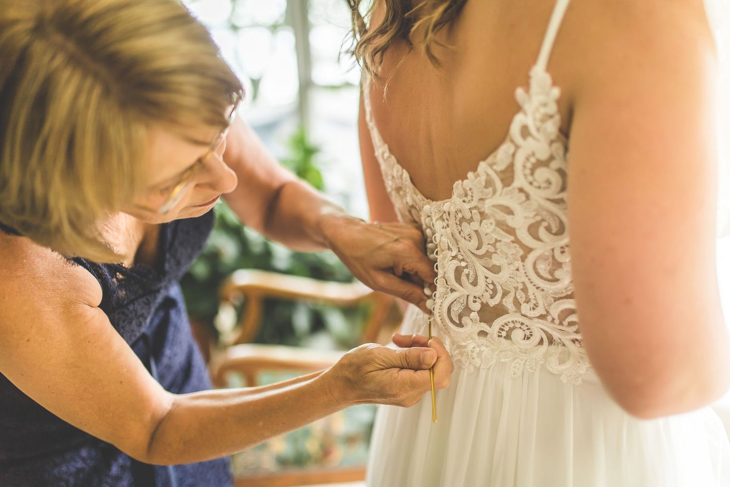 Close-up details of lace wedding dress being fastened.