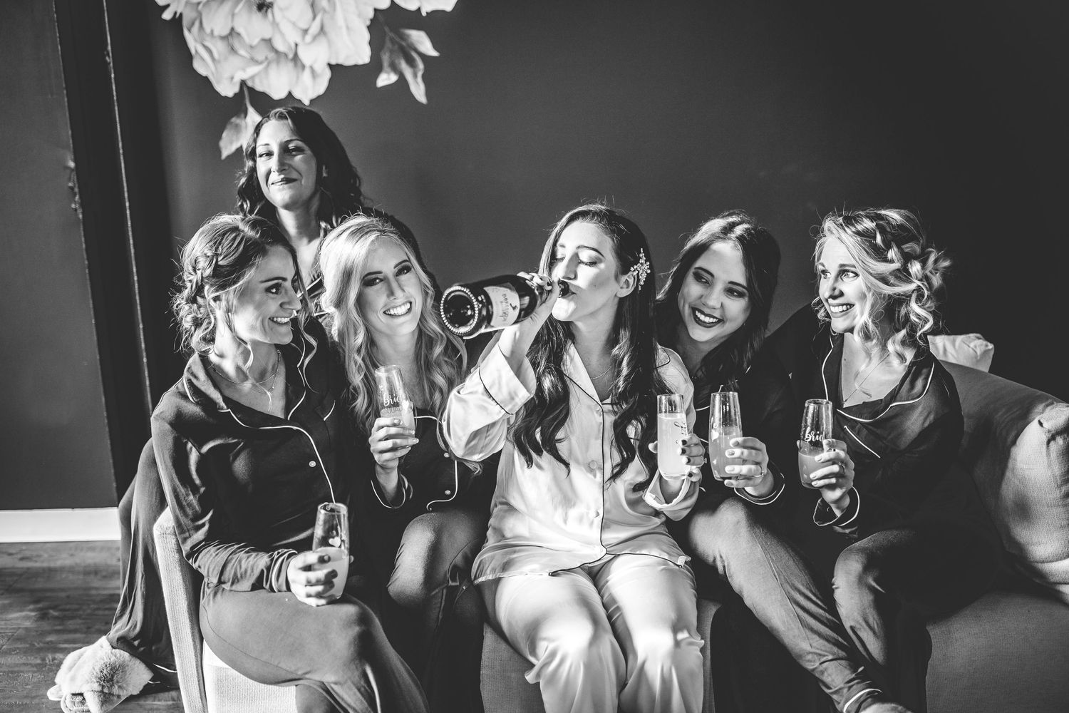 Dramatic black and white portrait of wedding party members sharing animated expressions.