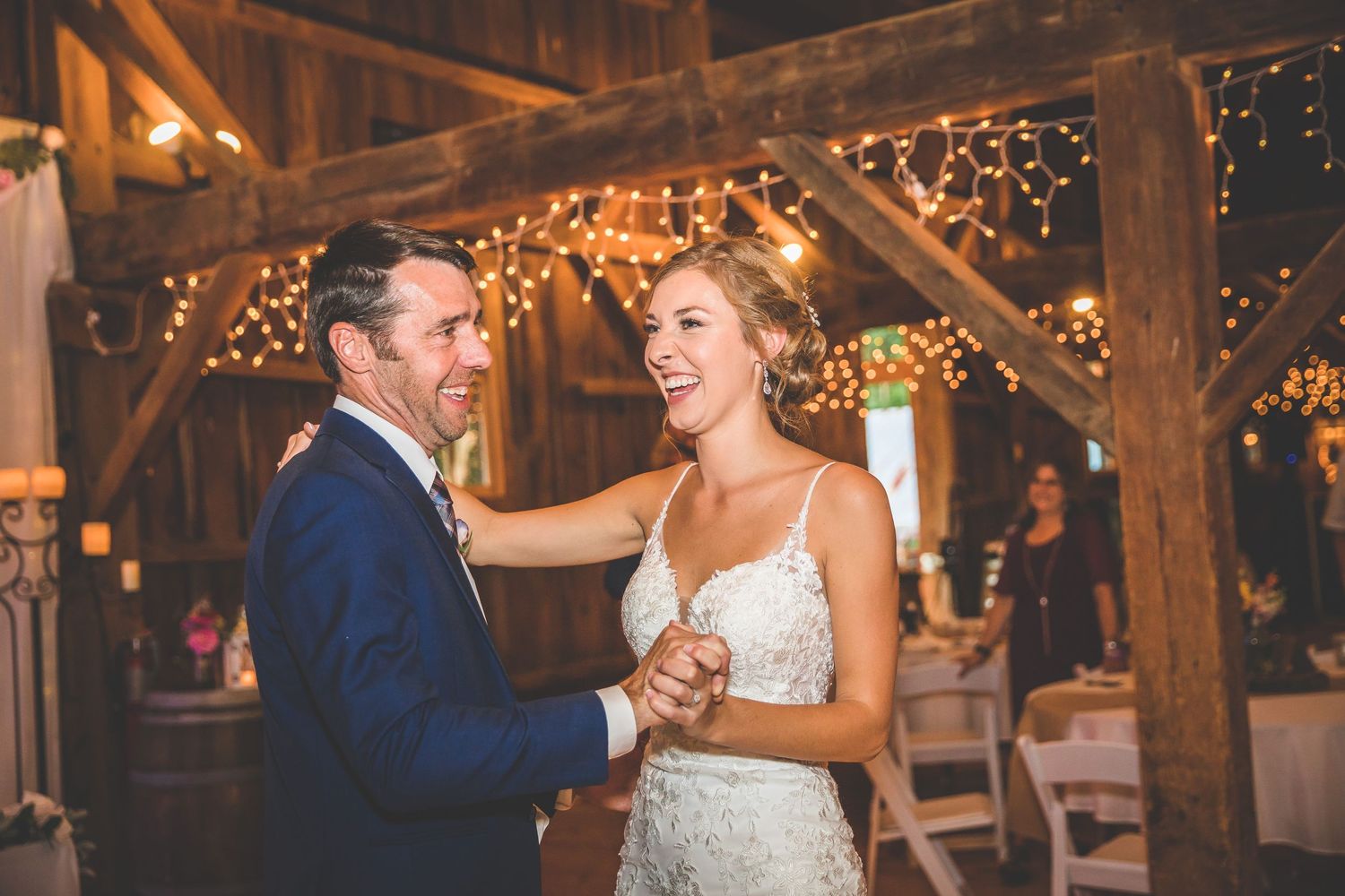 Couple sharing laughter during their dance in a rustic barn reception.