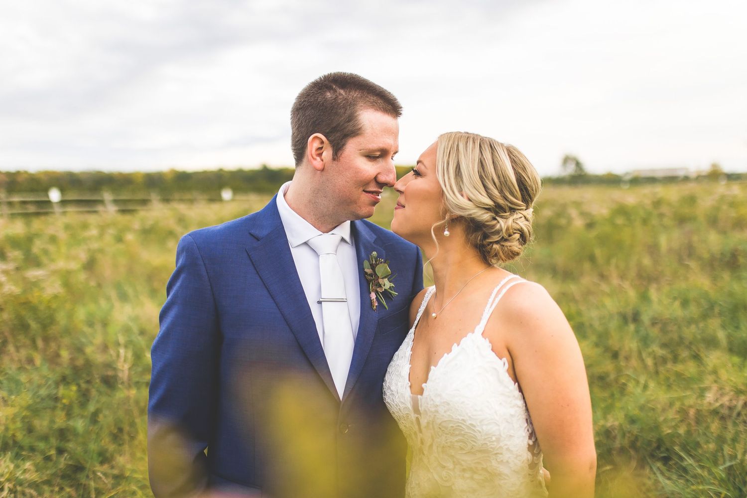 Couple shares tender moment in outdoor wedding setting with natural lighting.