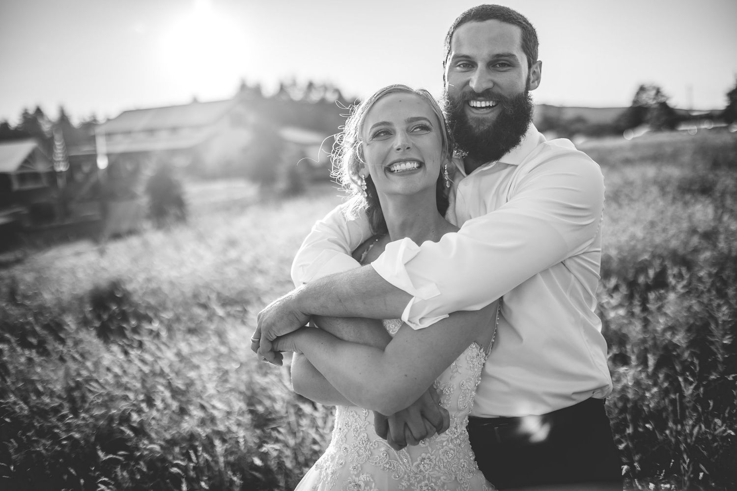 Couple embracing in a sunlit field during a summer evening photoshoot.