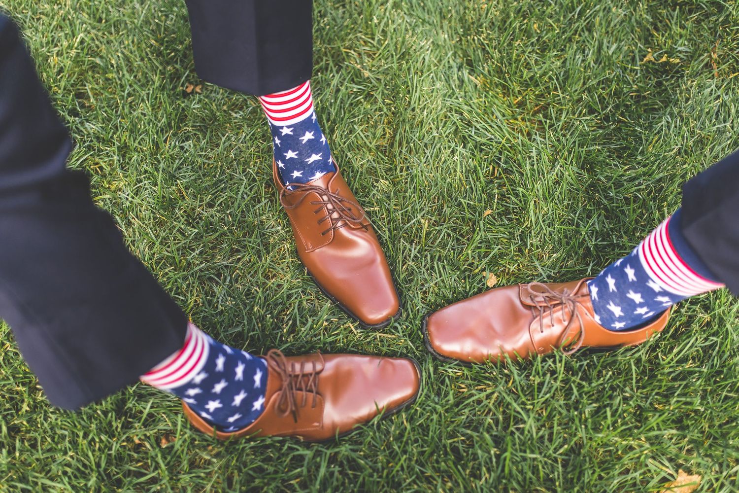 Fun detail shot of groomsmen showing off American flag socks with brown dress shoes.